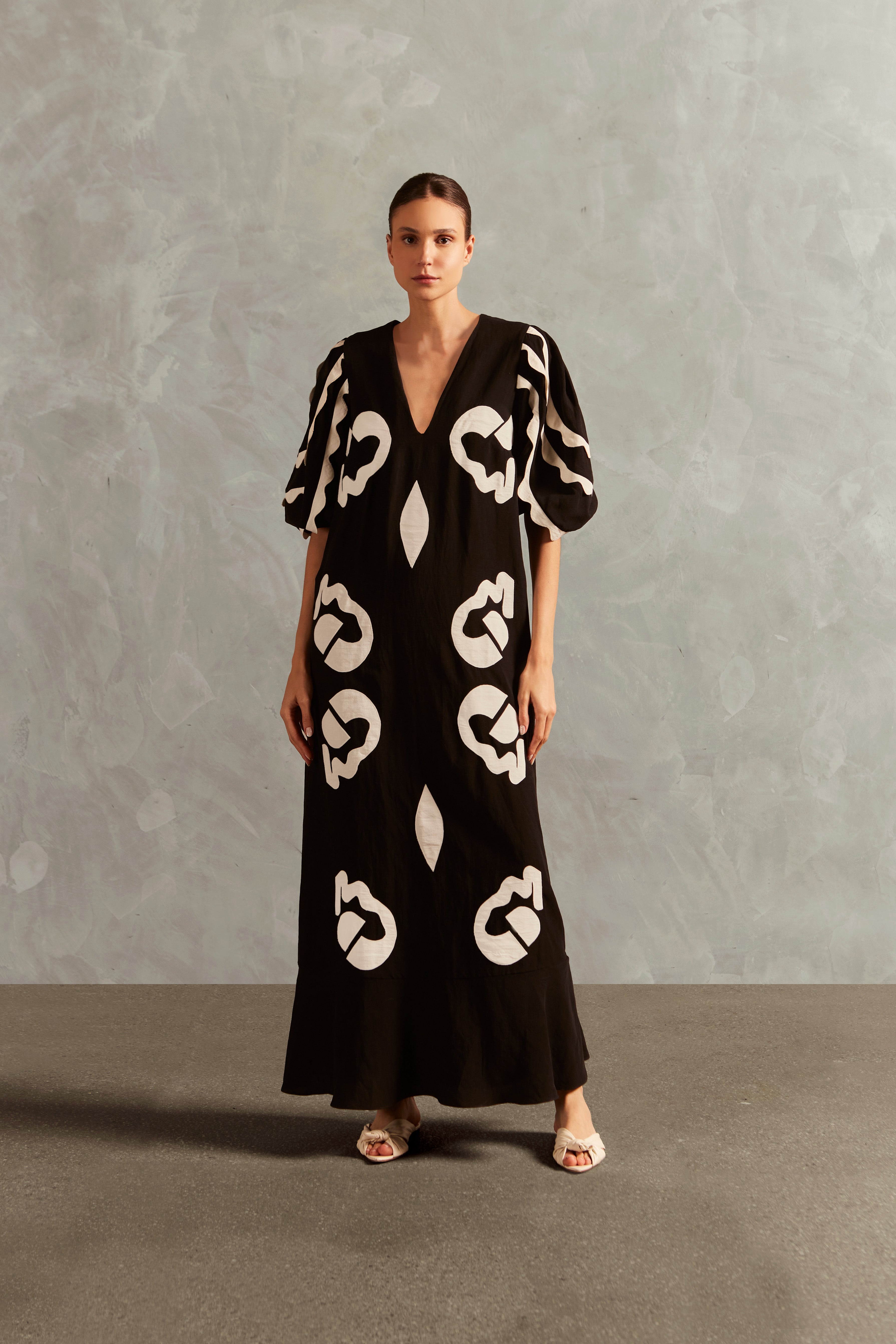 Model wearing the Appliqué V-Neck Long Dress Front showcasing its Black print on 55% Linen 45% Viscose fabric, styled for an afternoon look.