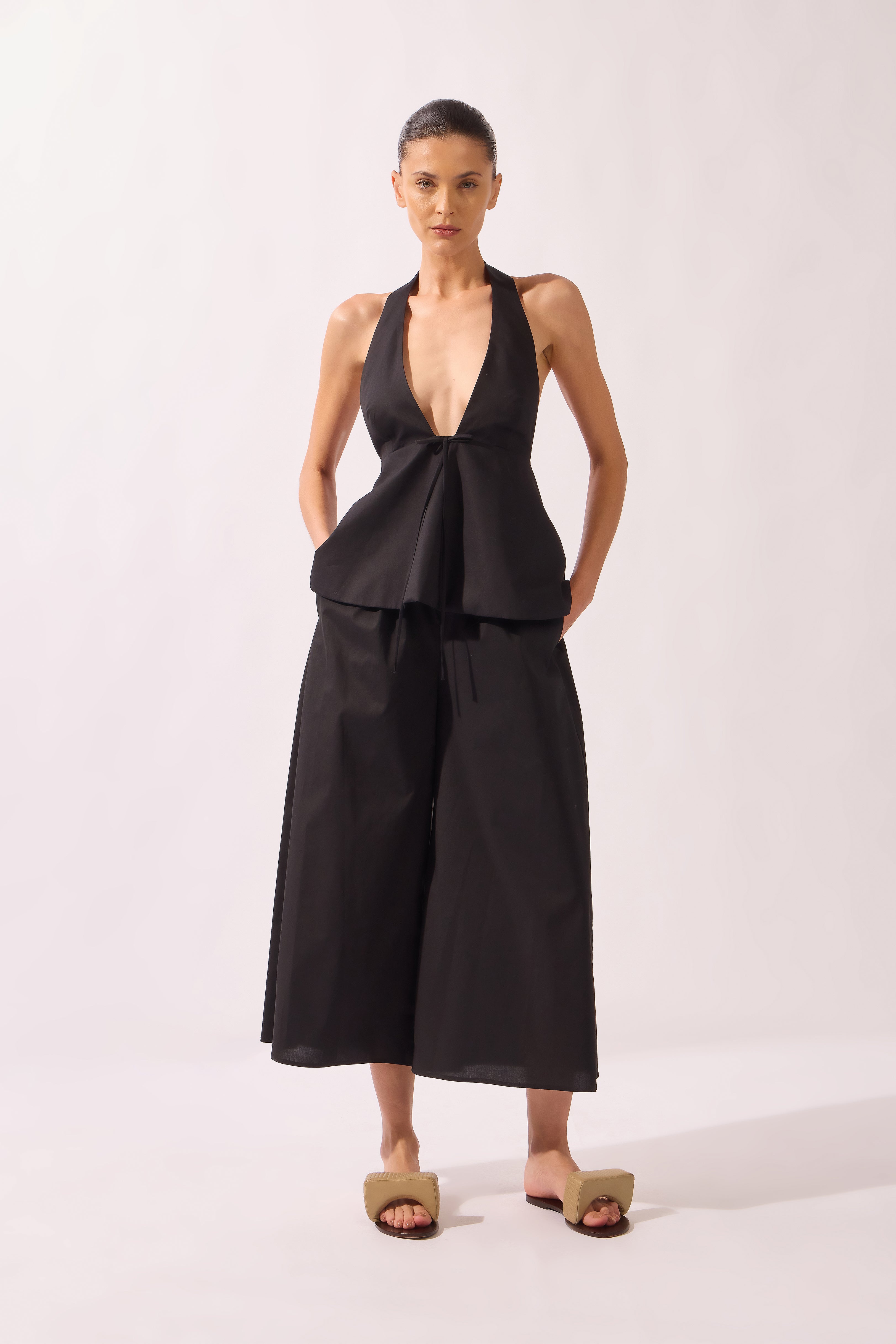 Model wearing the Peplum Cropped Wide-Leg Pants look color black made with 97% Cotton 3% Elastane, styled for resortwear look