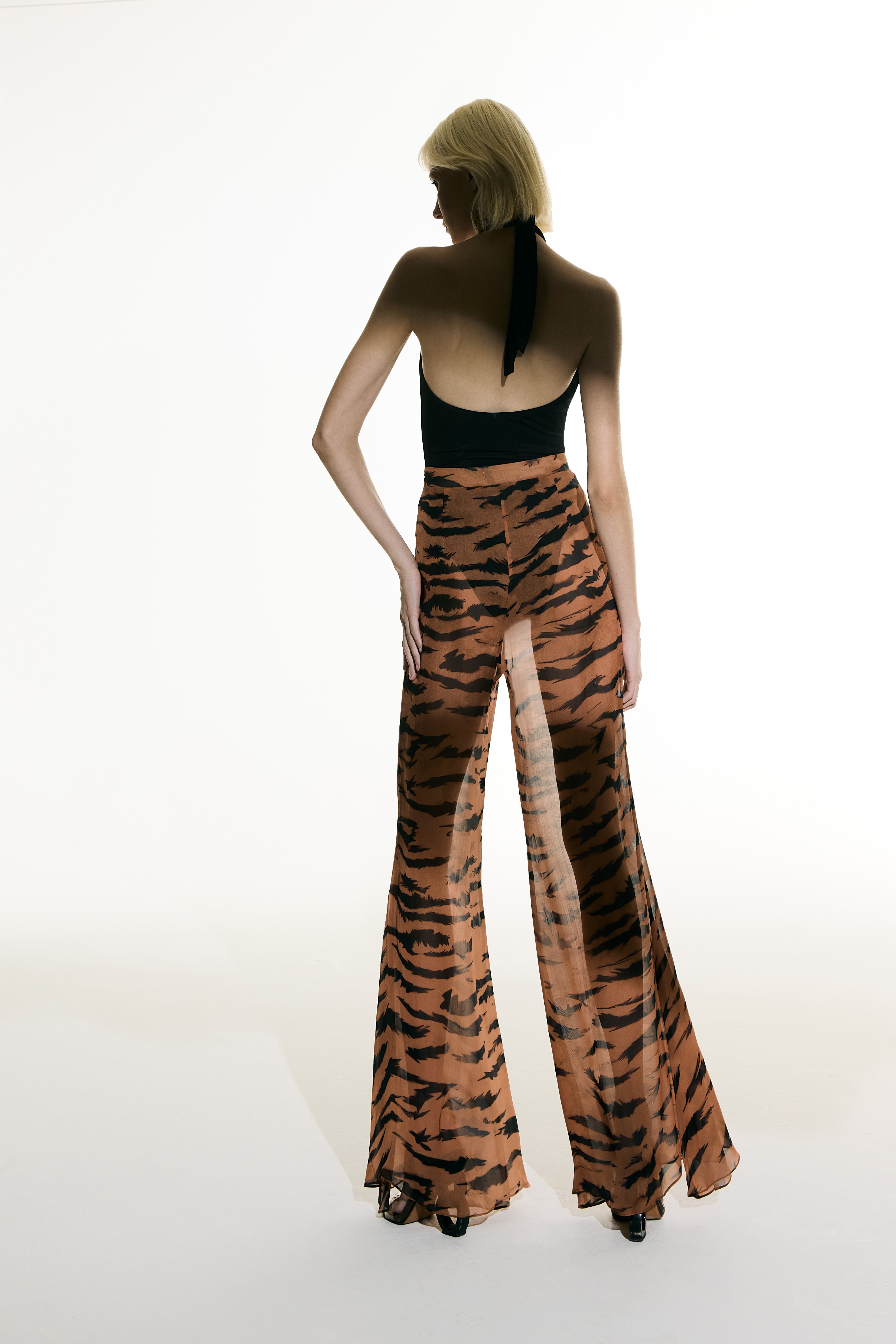 Model wearing the Flared Silk Pants back from the Adriana Degreas and Sabine Getty collab with 100% Silk styled for a casual look.