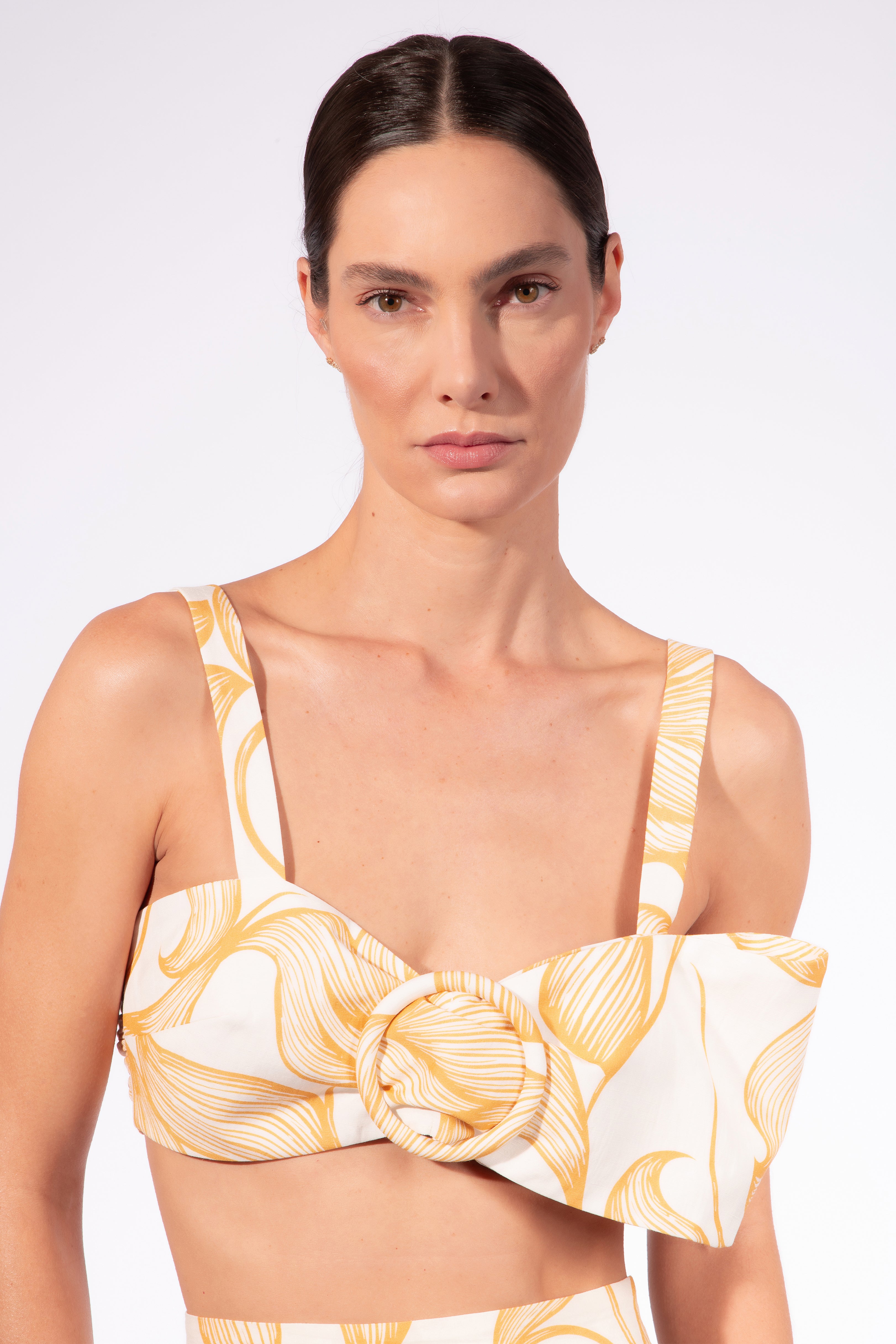 Model wearing the Foliage Bralette Top detail color cashew yellow, made from 55% linen 45% viscose, styled for a resort look