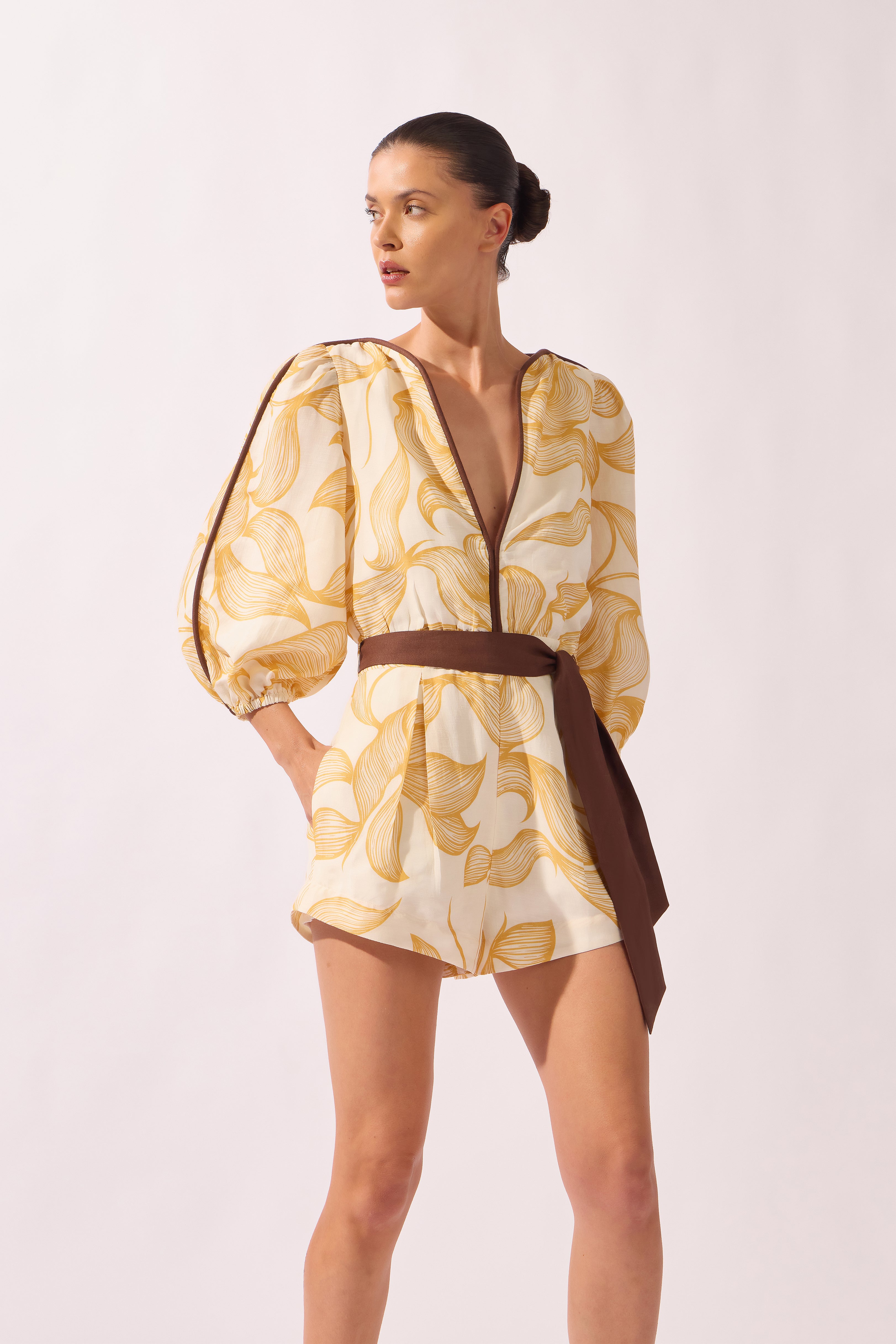 Model wearing the Foliage Romper front color cashew yellow, made from 55% linen 45% viscose, styled for a resort look