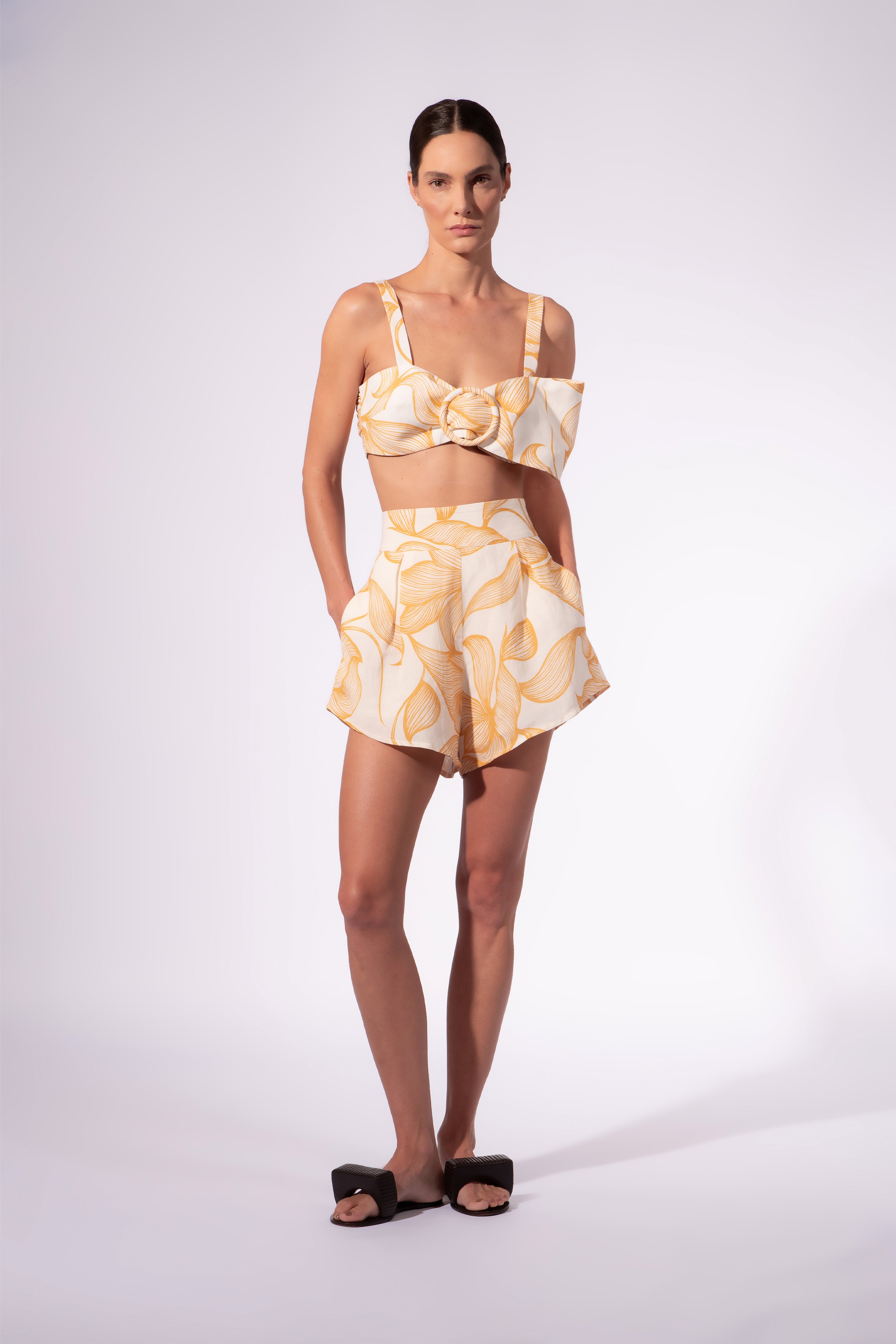 Model wearing the Foliage Shorts front color cashew yellow, made from 55% linen 45% viscose, styled for a resort look