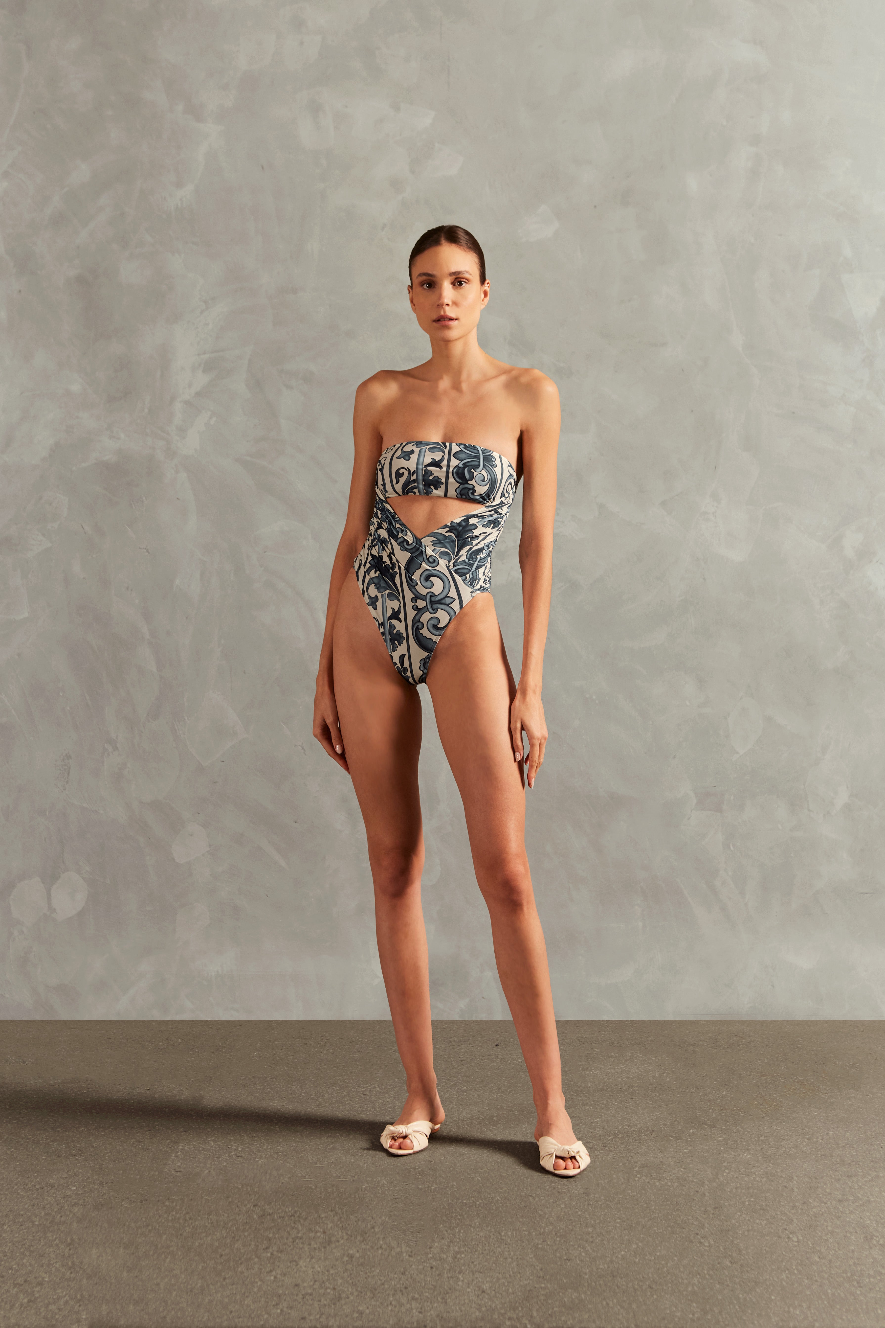 Model wearing the Hera High-Leg Strapless Swimsuit Front showcasing its BLUE color on 82% polyamide 18% spandex fabric, styled for a beachwear look.