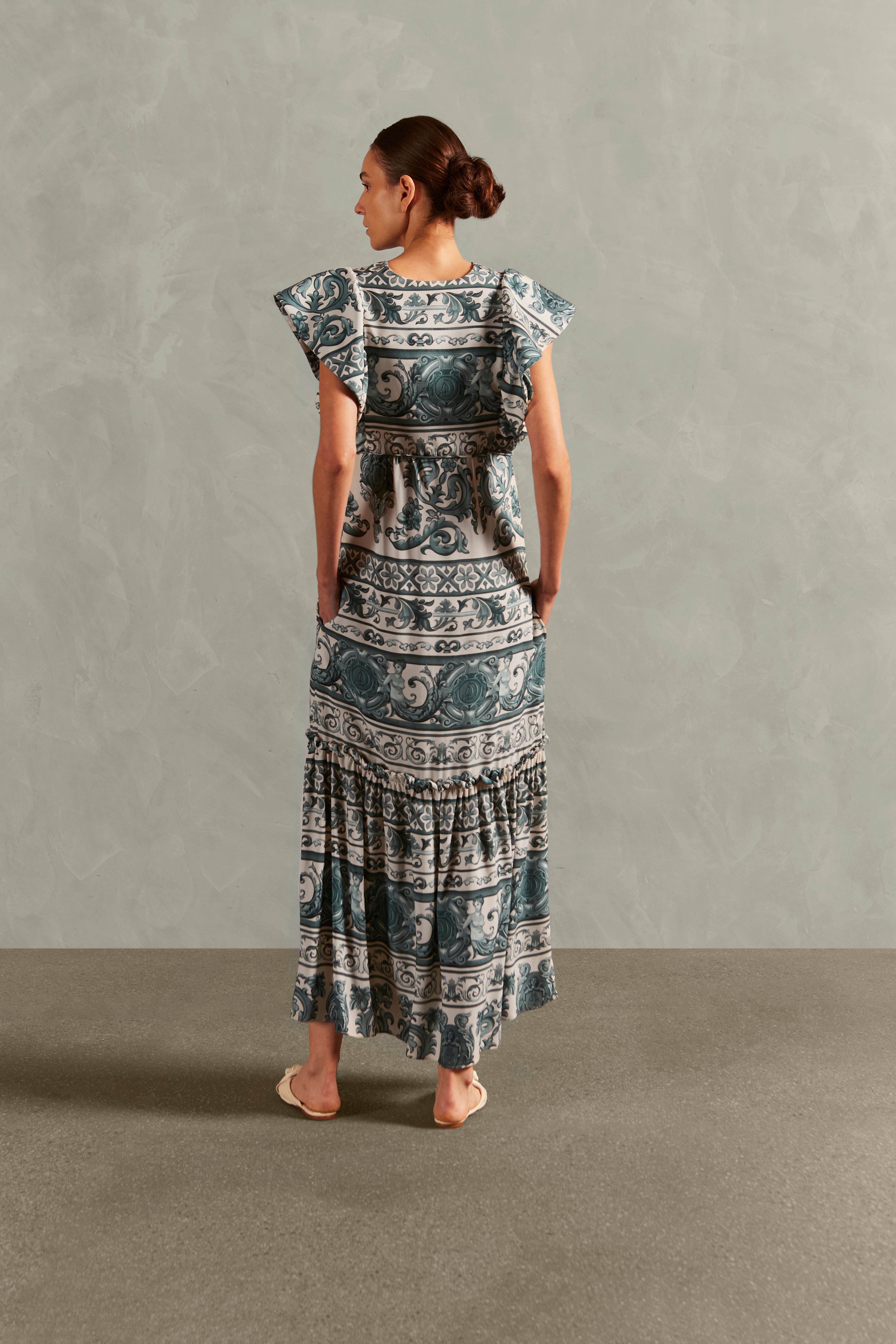 Model wearing the Hera Ruffled Long Dress color blue back, with 100% viscose fabric, styled for a resort look