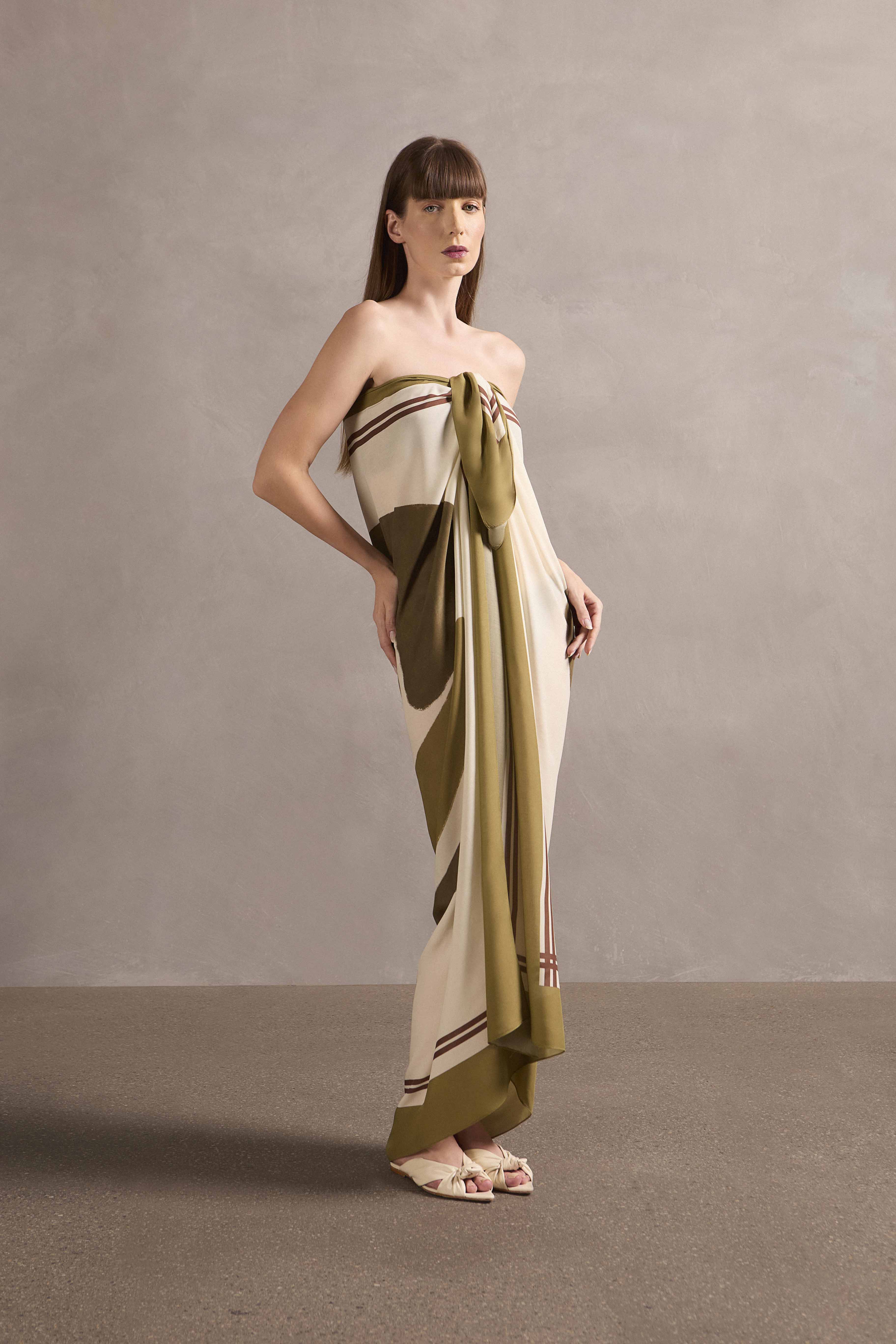 Model wearing the Mobile Lina Bo Bardi Panneaux showcasing its vintage references with green print on off-white 100% viscose fabric used as a dress, styled for a resort look.