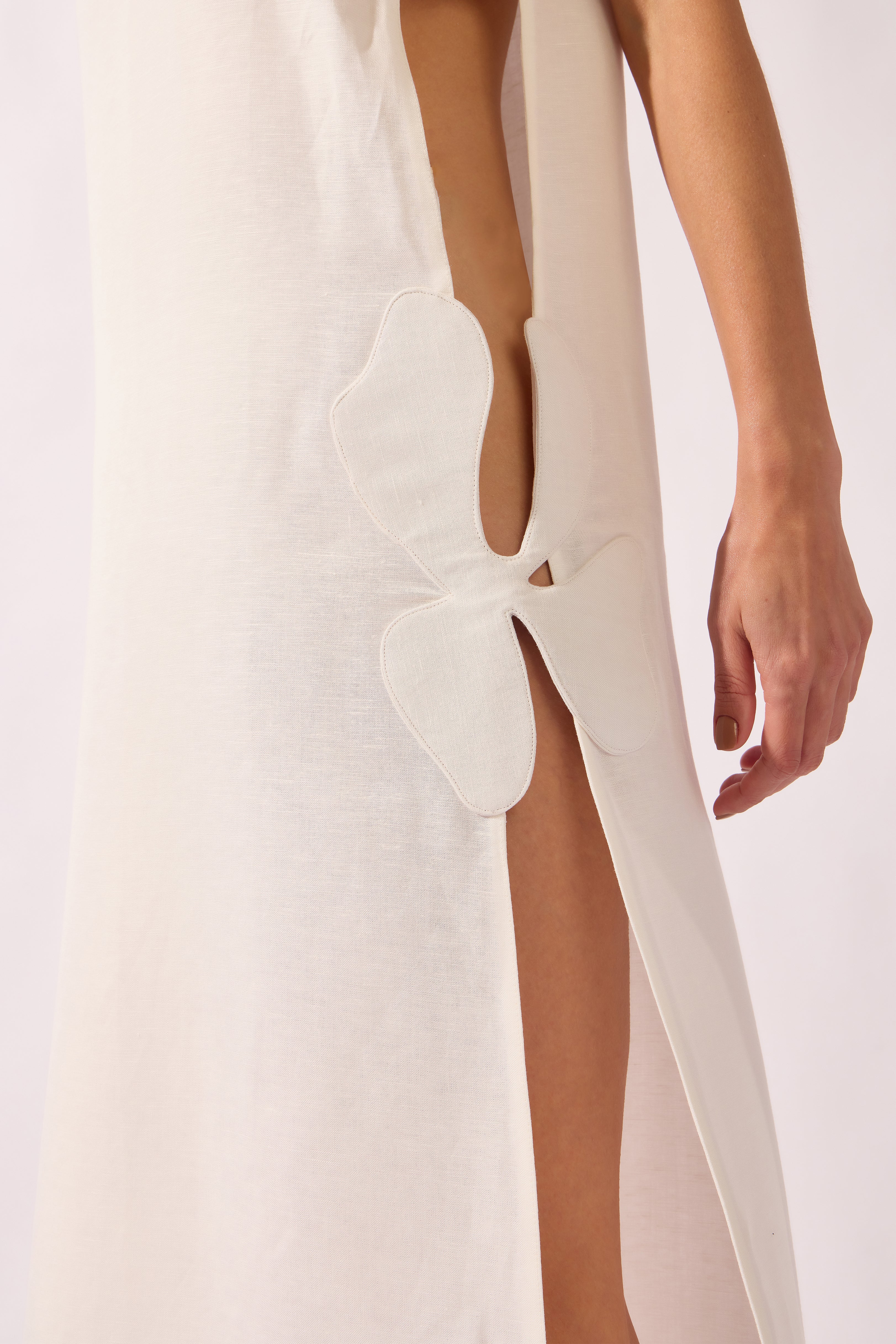 Model wearing the Open-Side Maxi Dress detail color off white, made from 55% linen 45% viscose, styled for a resort look