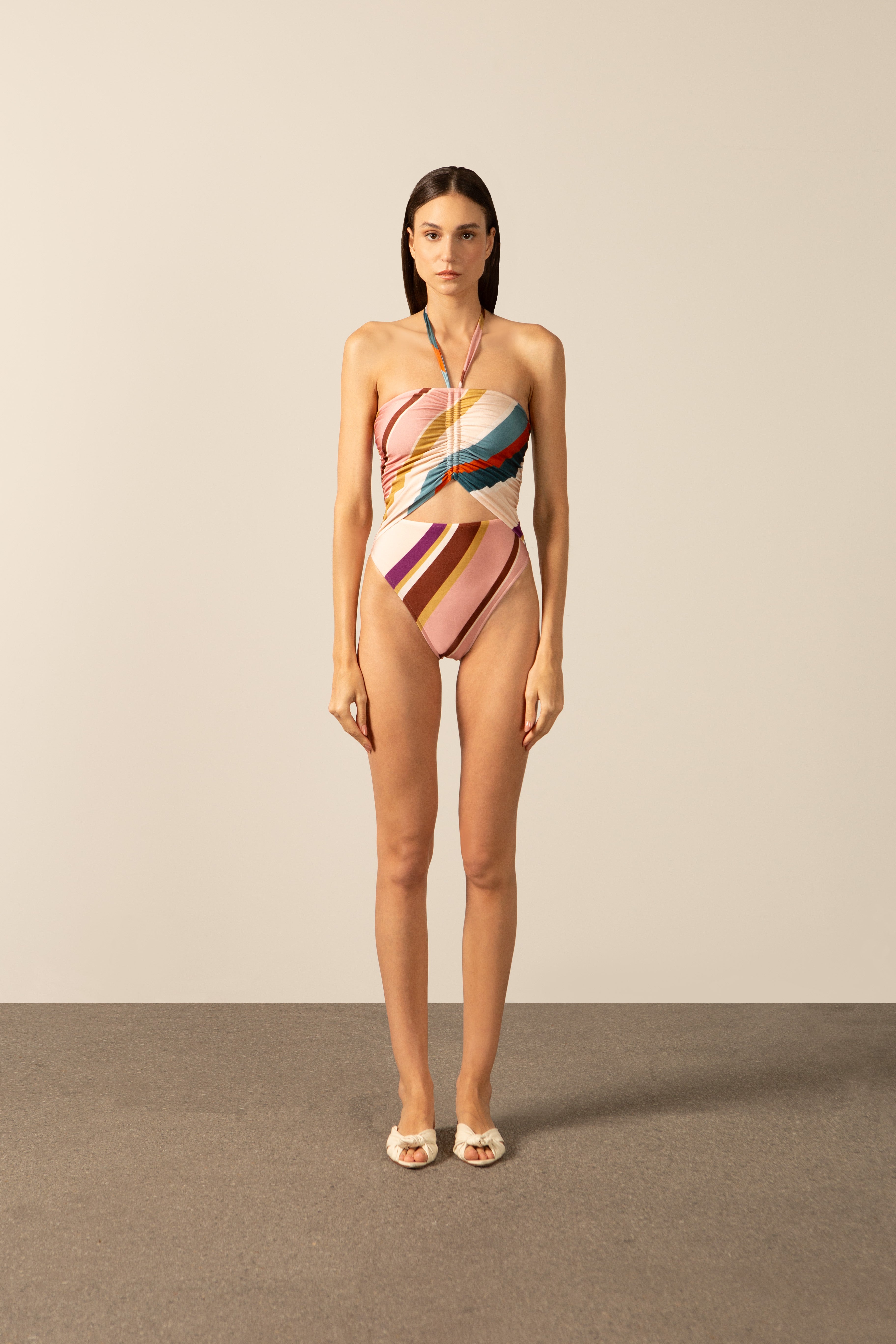 Model wearing the Organic Stripes Halterneck Swimsuit unique color front from the HS25 with 85% Polyamide 15% Elastane styled for a beach look.
