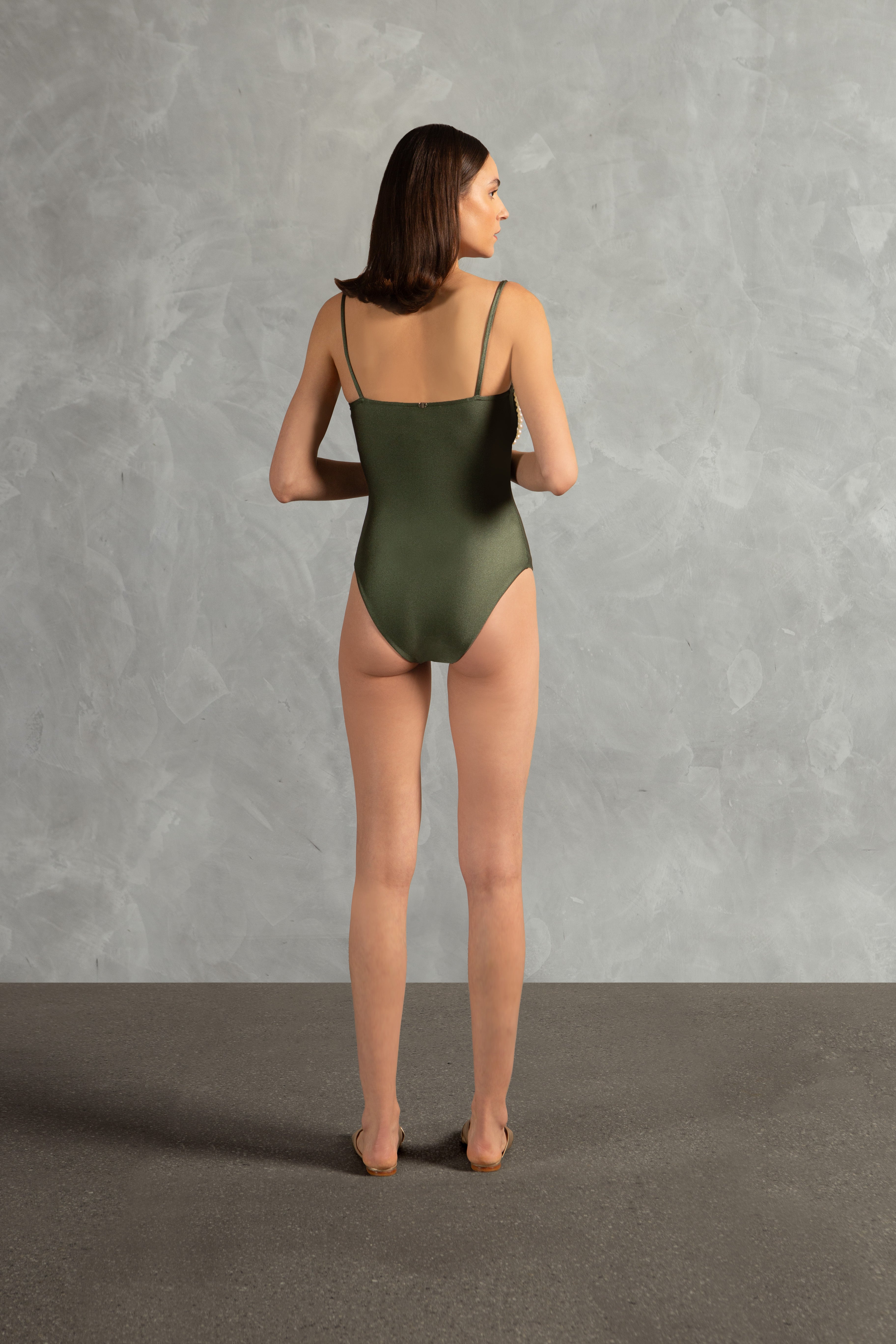 Model wearing the Oysters Solid Strapless Swimsuit With Pearls Back showcasing its Green print with Pearls Applications on 85% polyamide 15% spandex fabric, styled for a beachwear look.