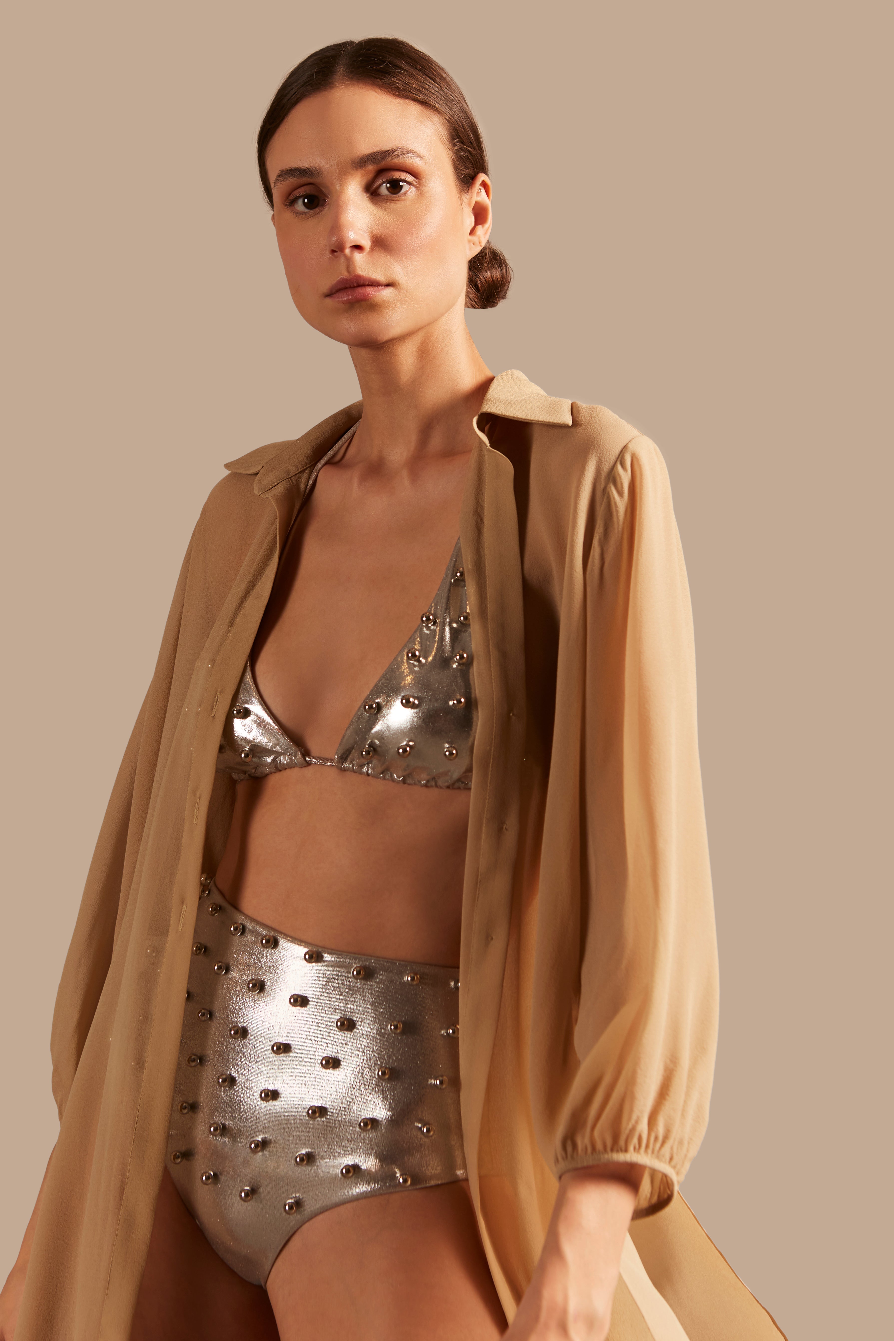 Model wearing the Oysters Solid Silver Lurex High-Waisted Bikini With Pearls showcasing the close up of it's redesigned version, on stretchy fabric, combined with a silk kaftan.