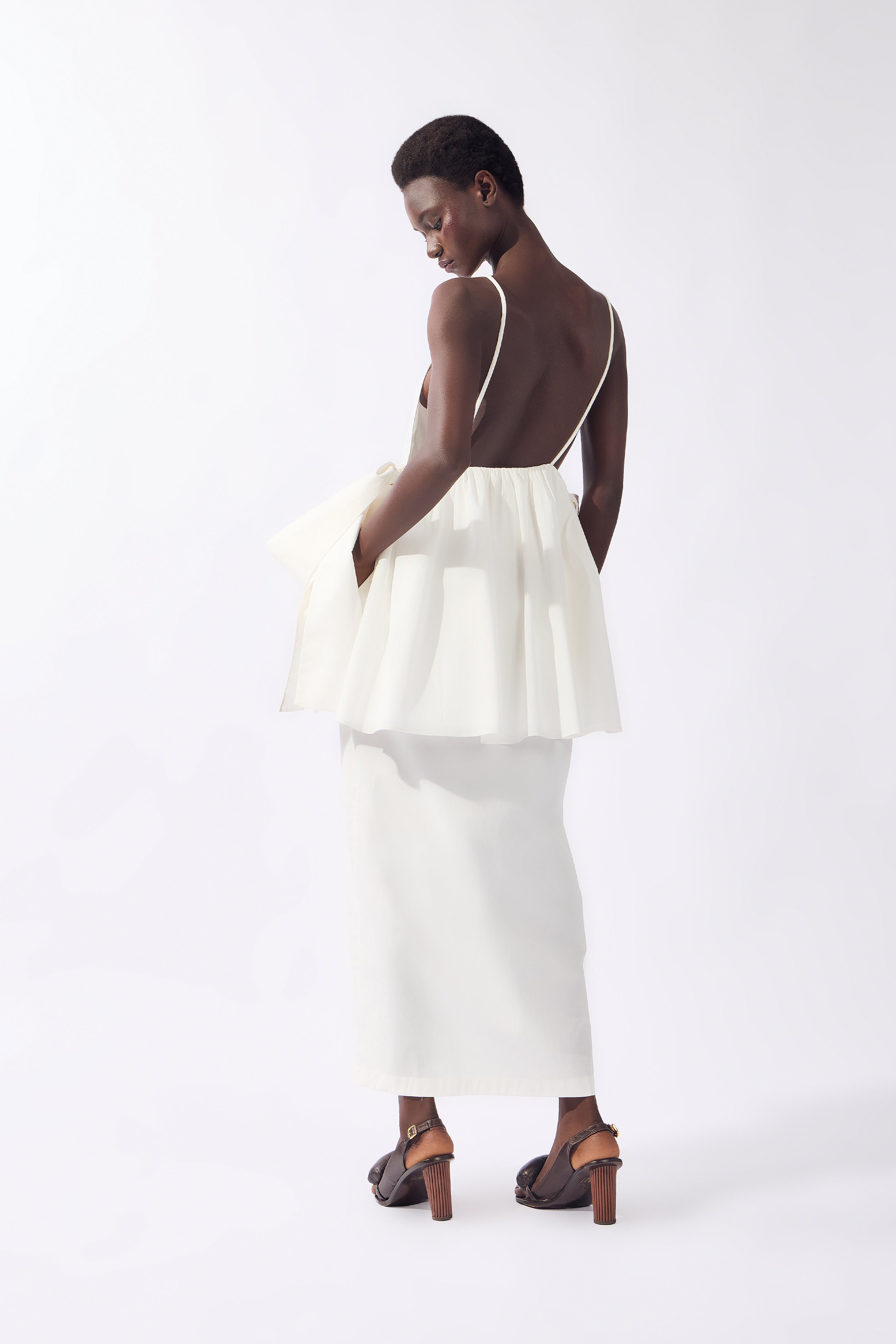 Model wearing the Peplum Maxi Dress back color off white, made from 98% cotton 2% elastane, styled for resort look