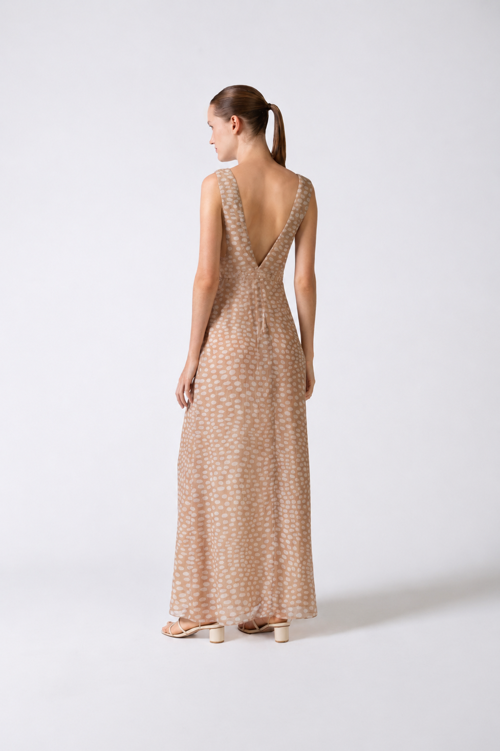Model wearing the Pois Plunge-Neck Long Dress back color beige, made from 100% silk, styled for a night out look