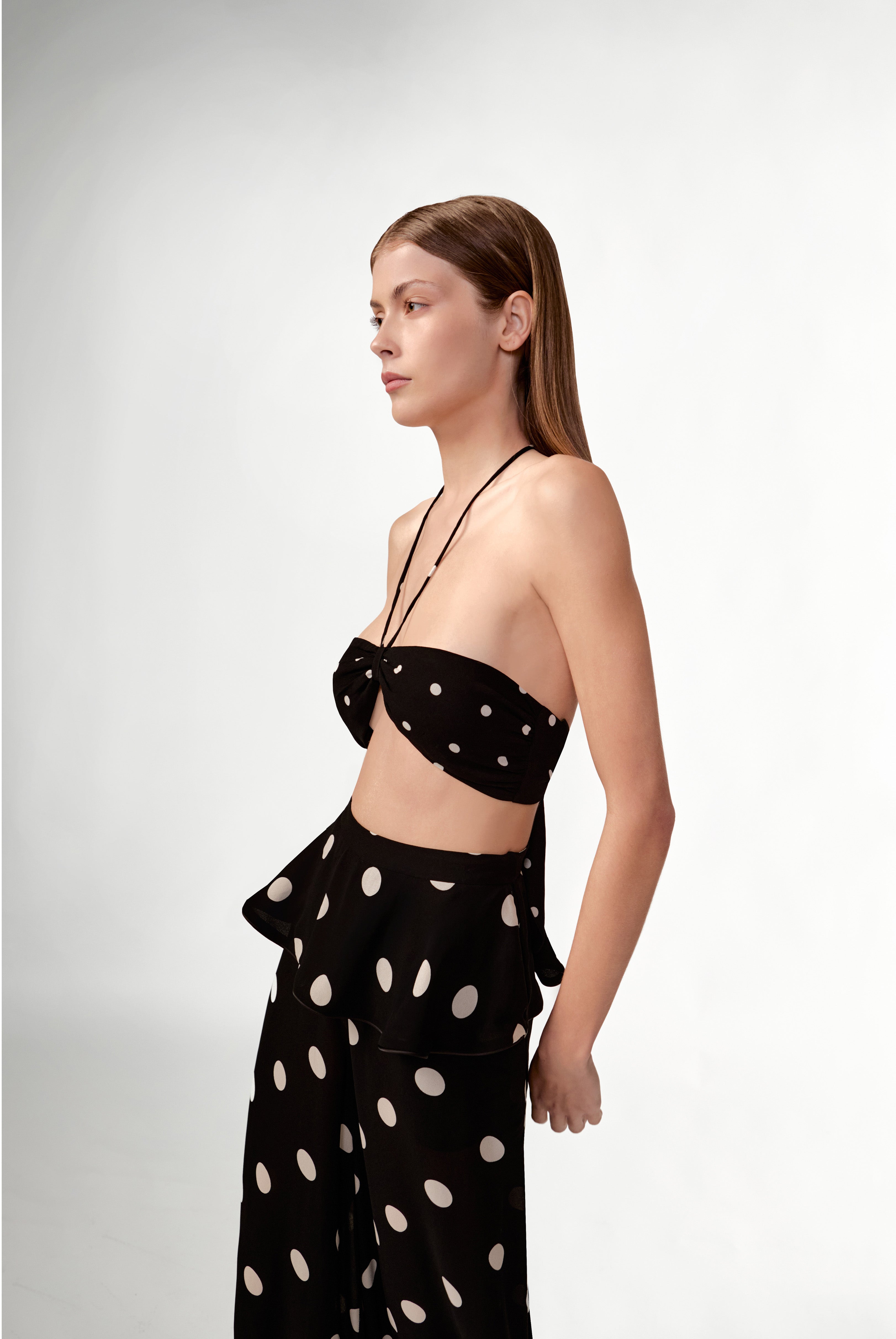 Model wearing the Polka Dots Bandeau Top side color black, made with 100% viscose fabric, styled for resortwear look