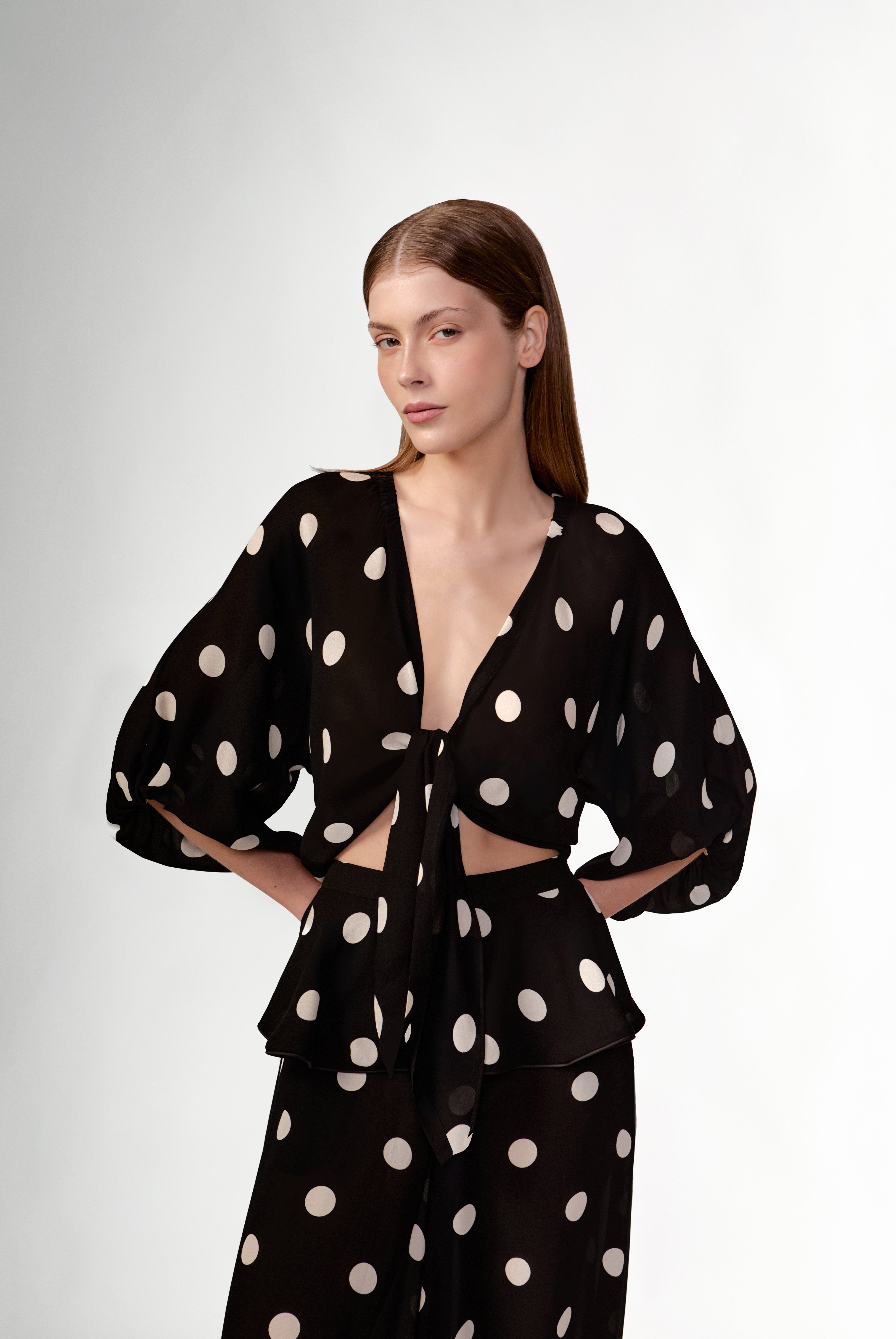 Model wearing the Polka Dots Front-Tie Cropped Top detail color black made with 100% viscose, styled for resortwear look