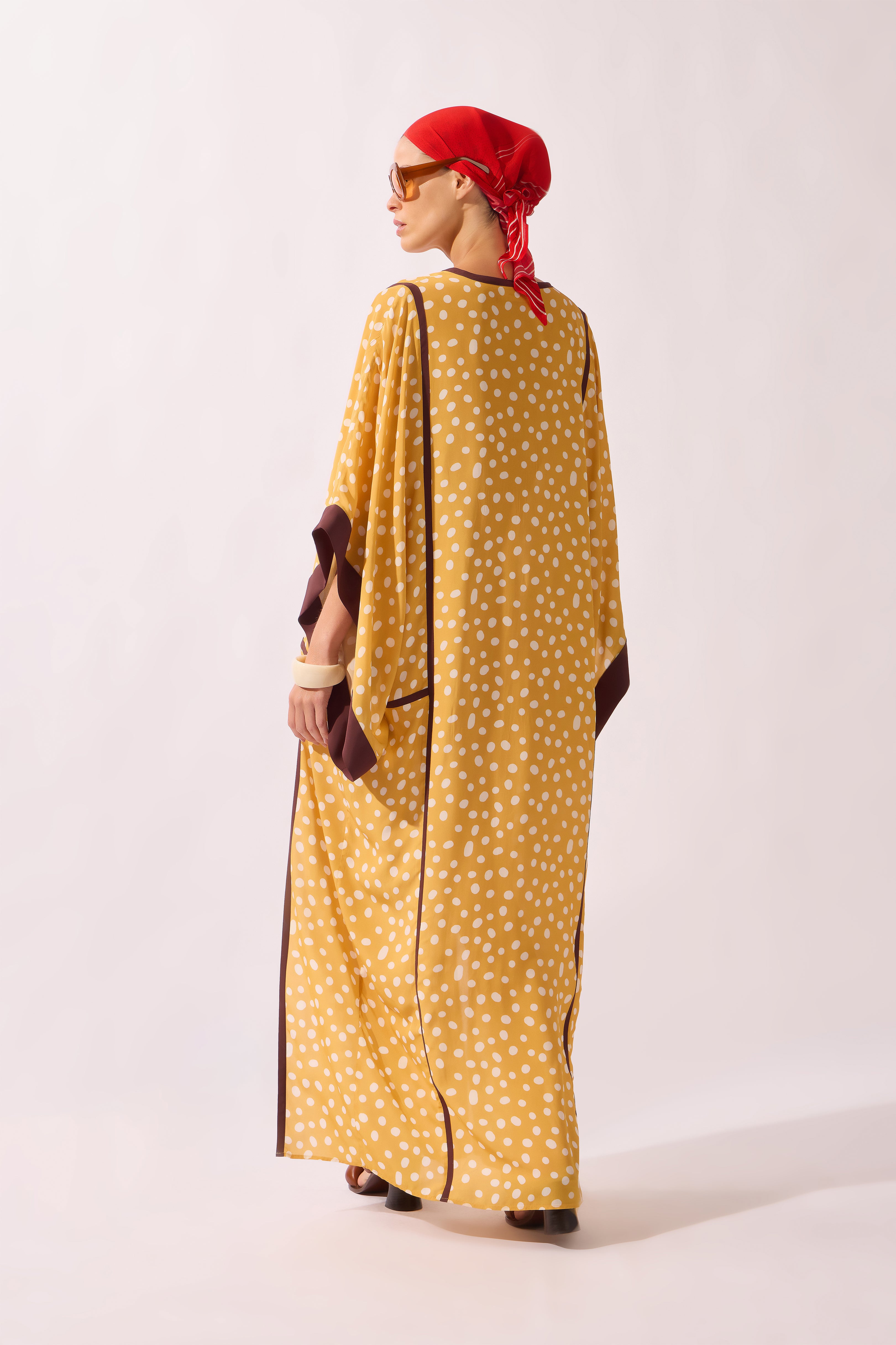 Model waering the Polka Dots Maxi Kaftan back, showcasing its yellow 100% viscose fabric, styled for a resort look.