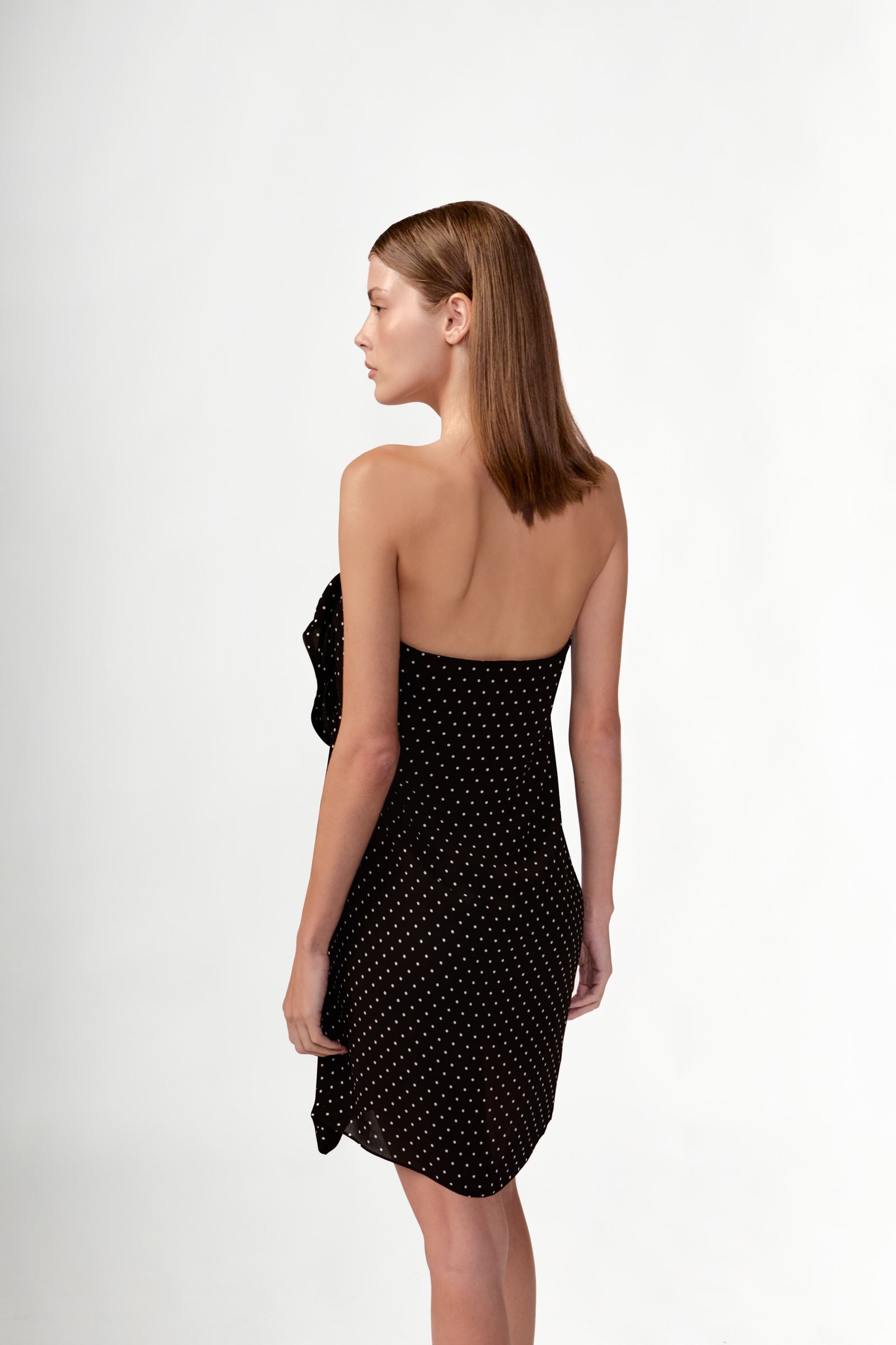 Model wearing the Polka Dots Mini Dress back color black, made with 100% viscose fabric, styled for resortwear look