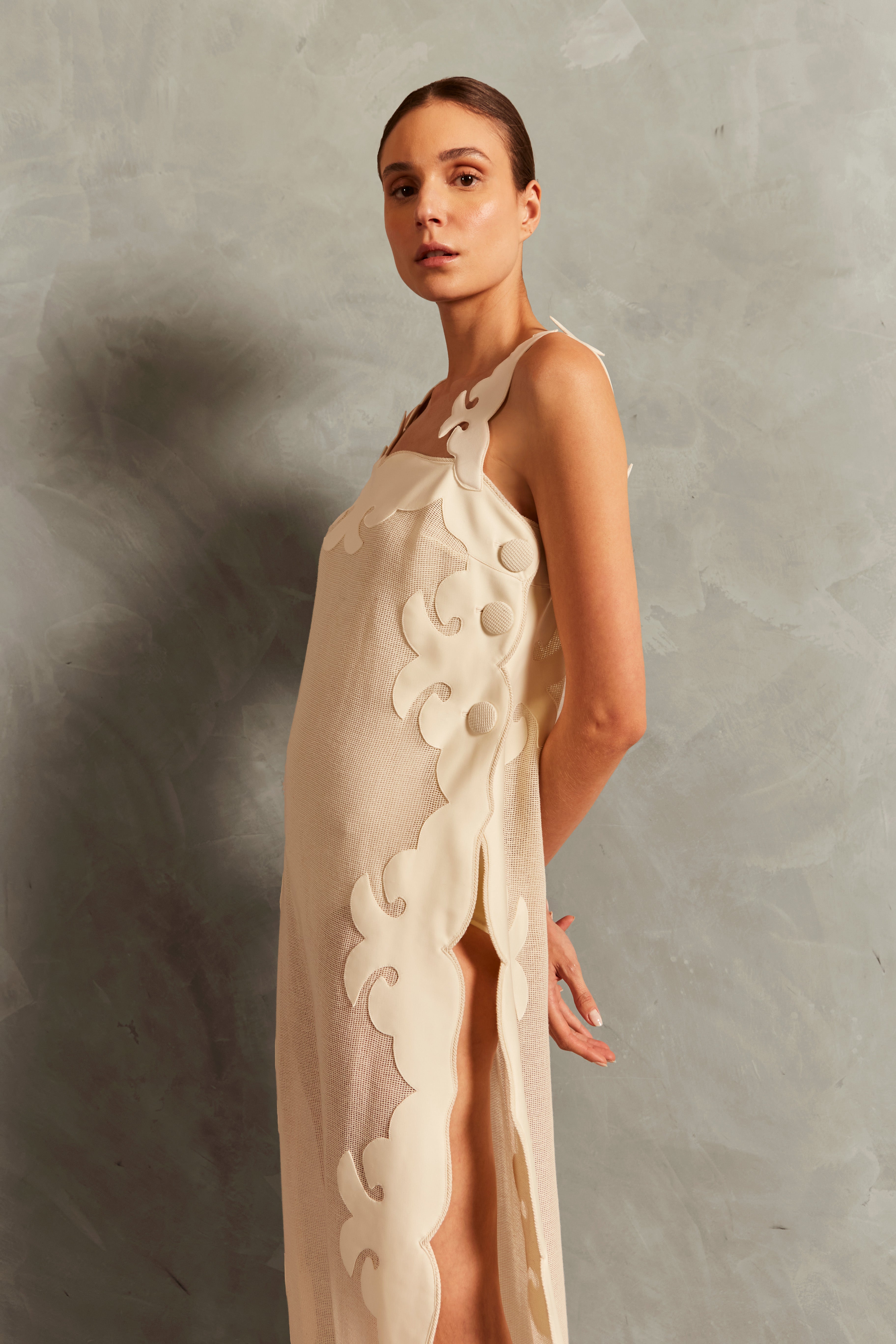 Model wearing the Réseau Appliqué Midi Dress concept showcasing its off white color with sheer fabric styled for a post-beach look