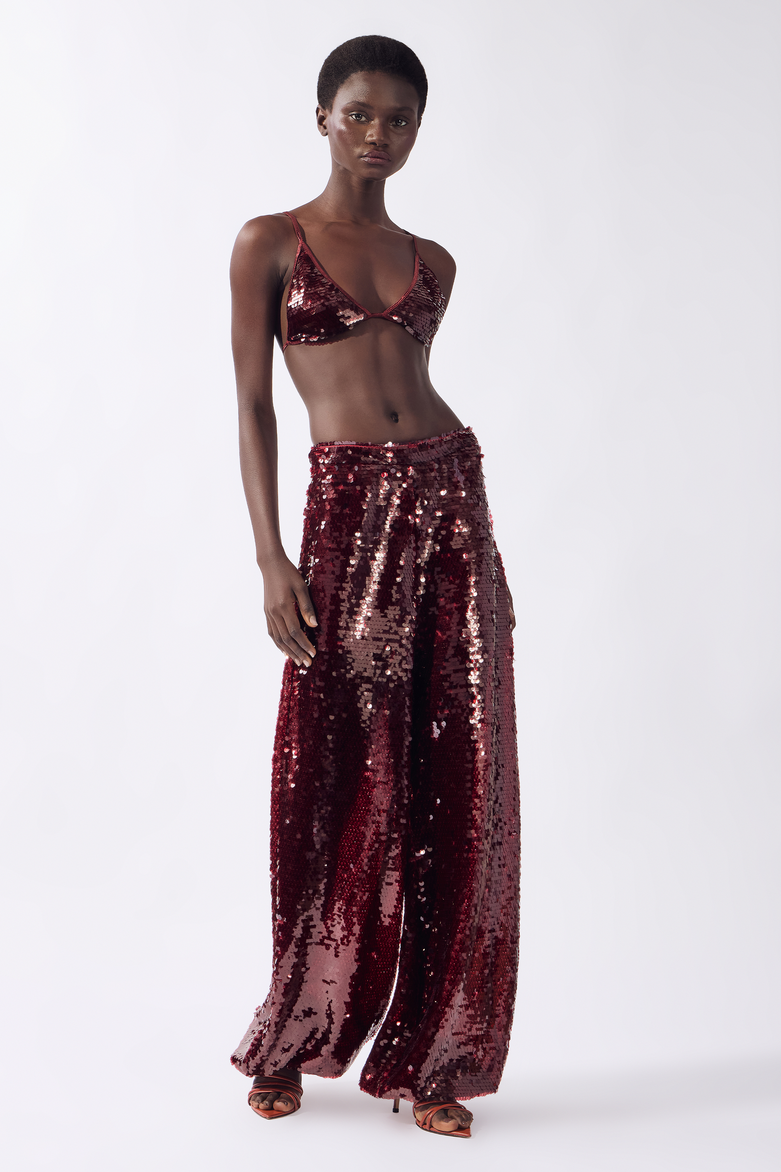 Model wearing the Sequin Bralette Top front color burgundy, made from 100% polyester, styled for a festive look
