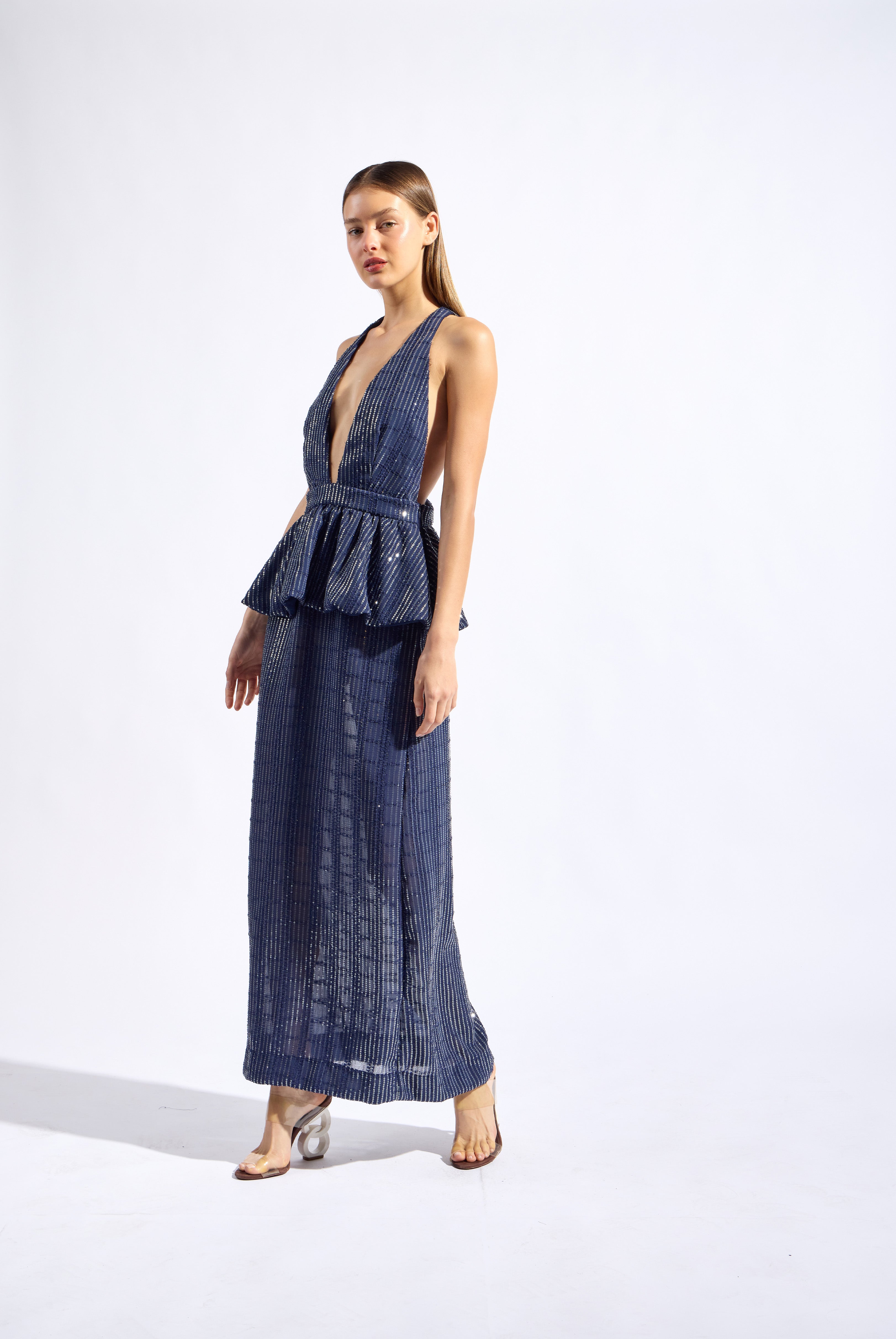 Model wearing the Sequin Deep V-Neck Peplum Maxi Dress look color navy made from 100% polyester fabric, styled for a resort look