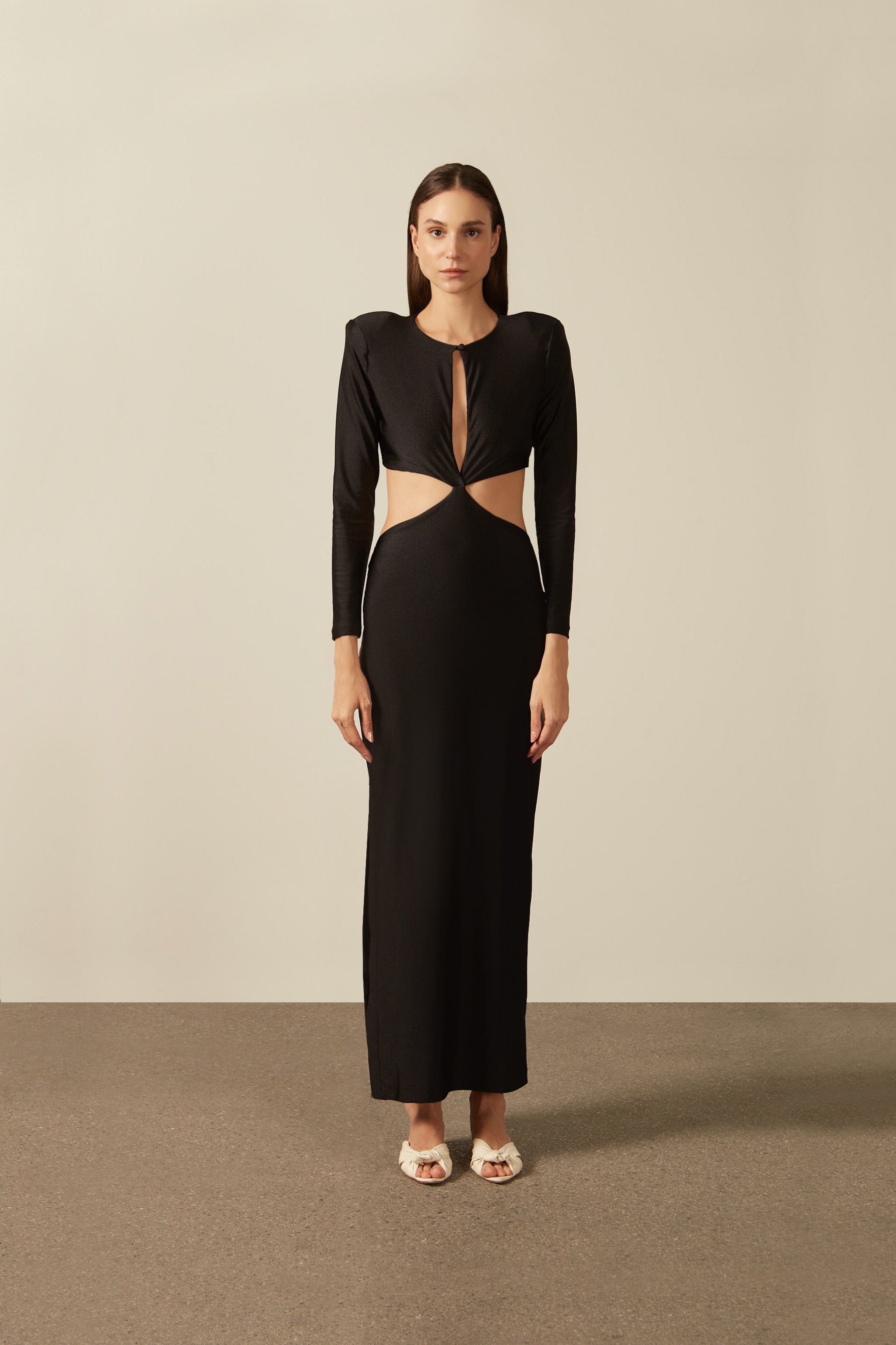 Model wearing the Solid Cut-Out Long Dress Front showcasing its Black color on 85% Polyester 15% Elastane fabric, styled for an evening look.