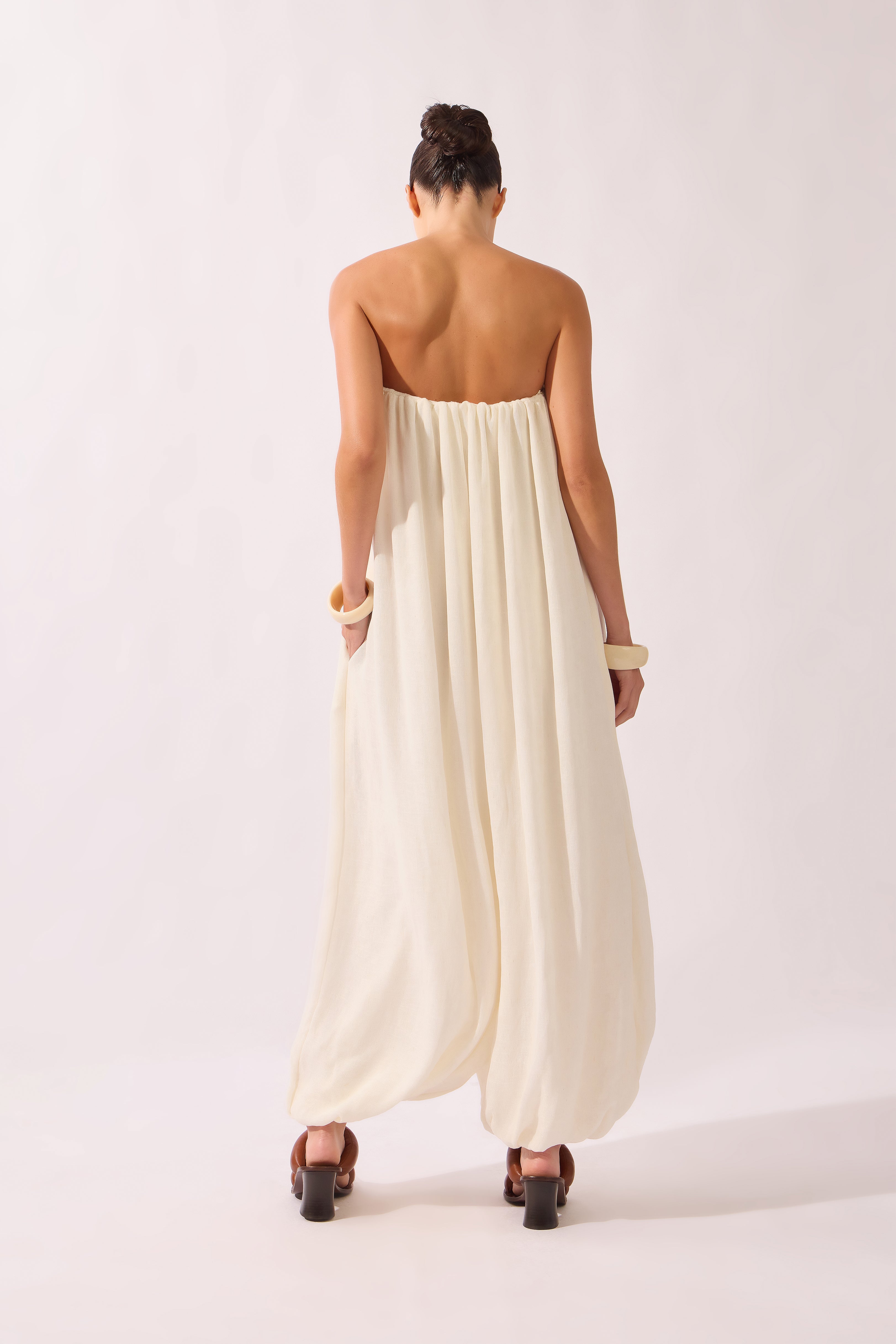 Model waering the Solid Maxi Jampsuit back, showcasing its off-white 70% Viscose 17% Polyamide 13% Linen fabric, styled for a resort look.