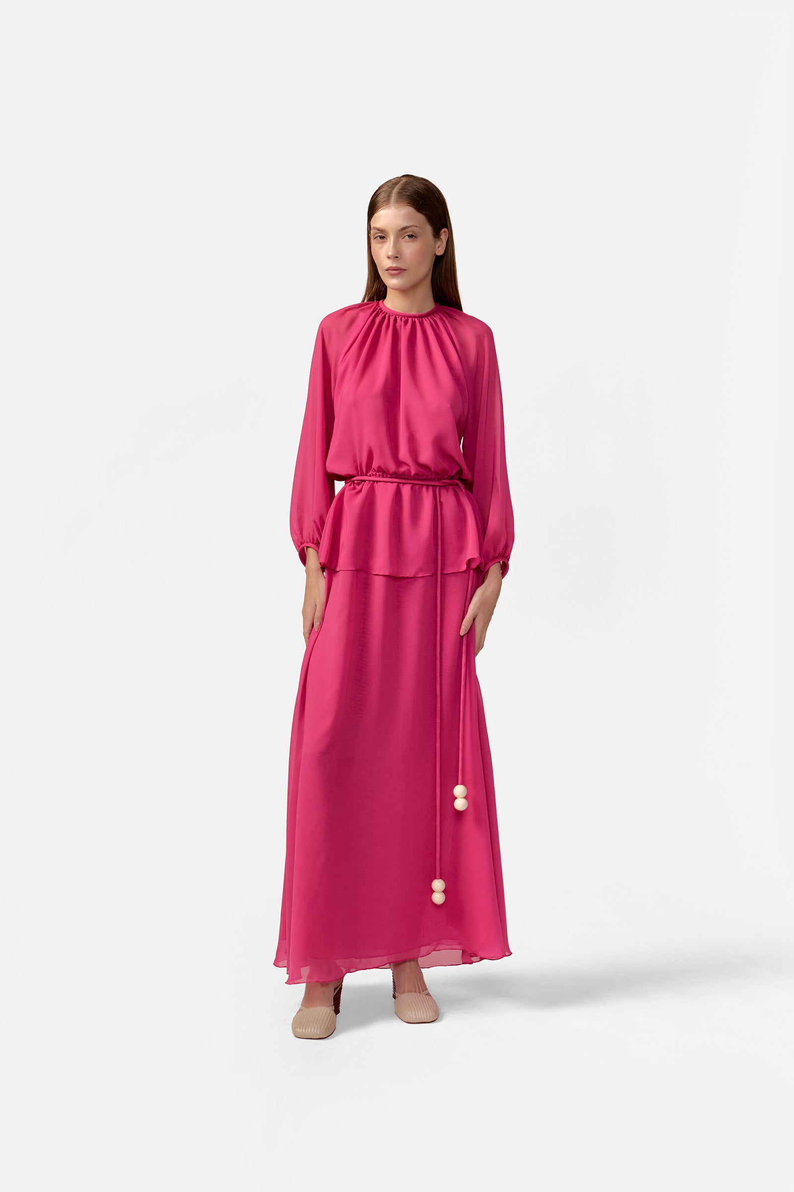 Model wearing the Solid Peplum Maxi Dress front color pink made with 100% Cotton, styled for resortwear look