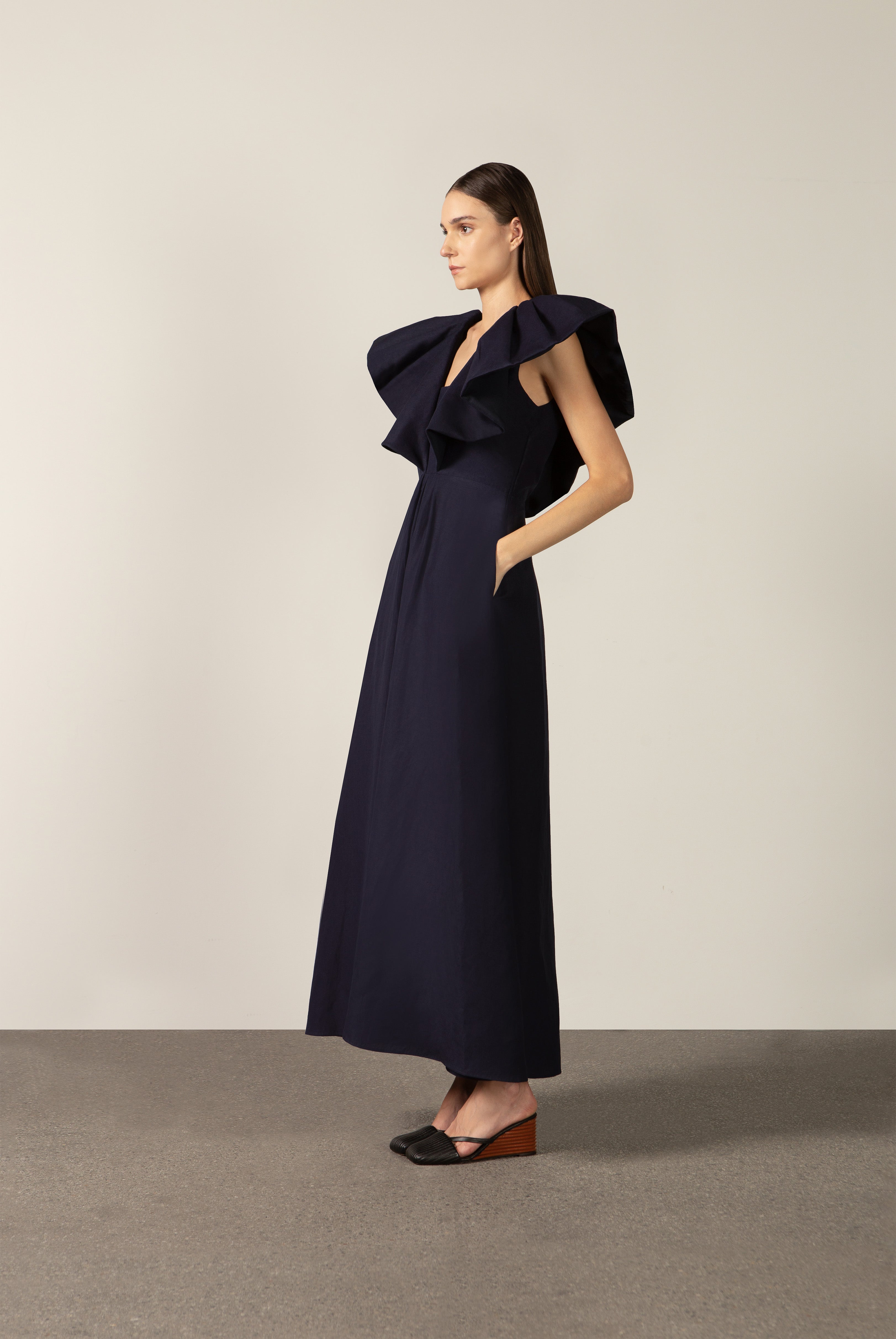 Model wearing the Solid Ruffled Maxi Dress side color navy made with 55% viscose 45% Linen, styled for resortwear look