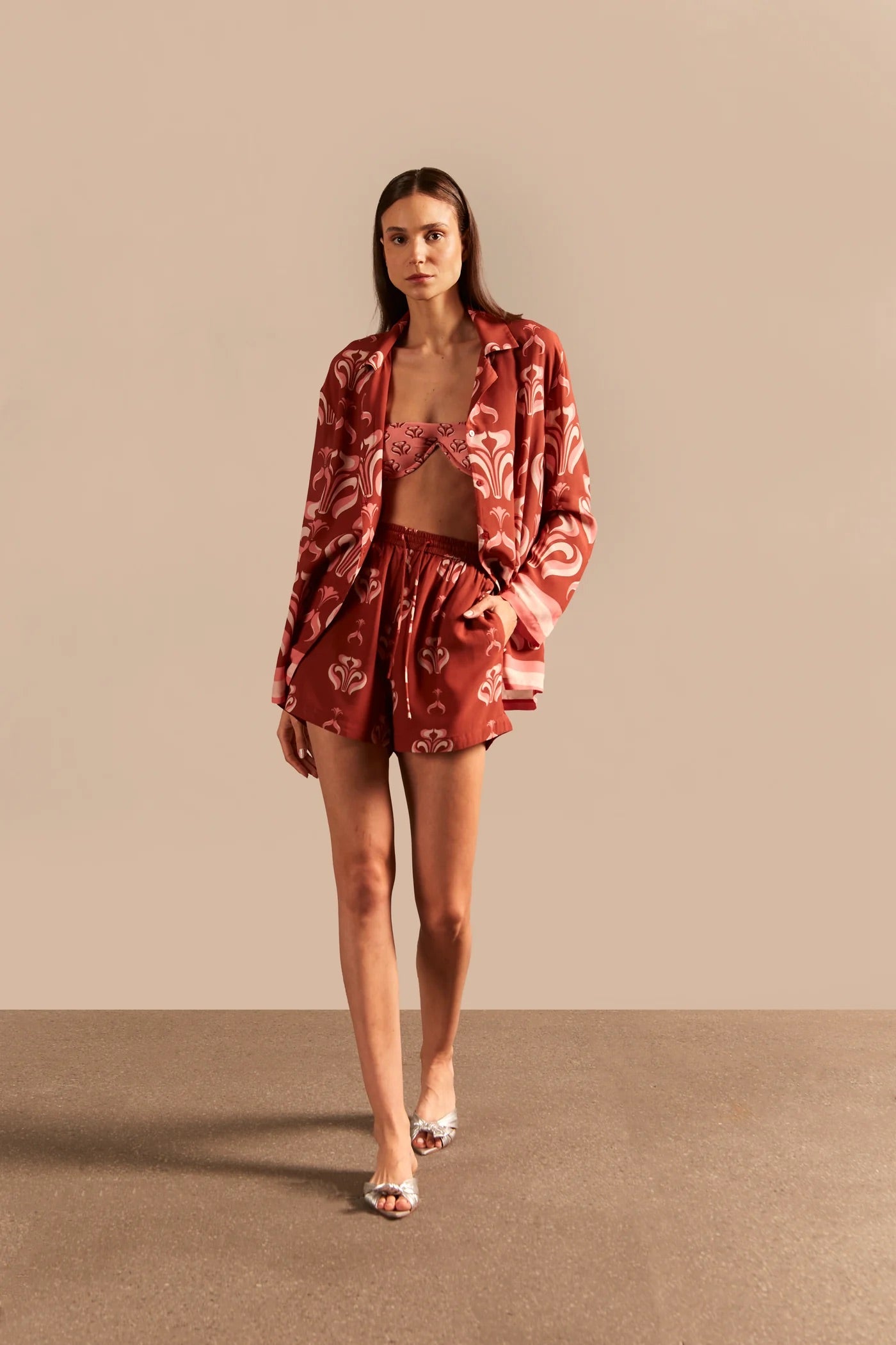 Model wearing the Vintage Lily Shorts showcasing the front of it's vintage-inspired dark red and pink print, on a viscose fabric.