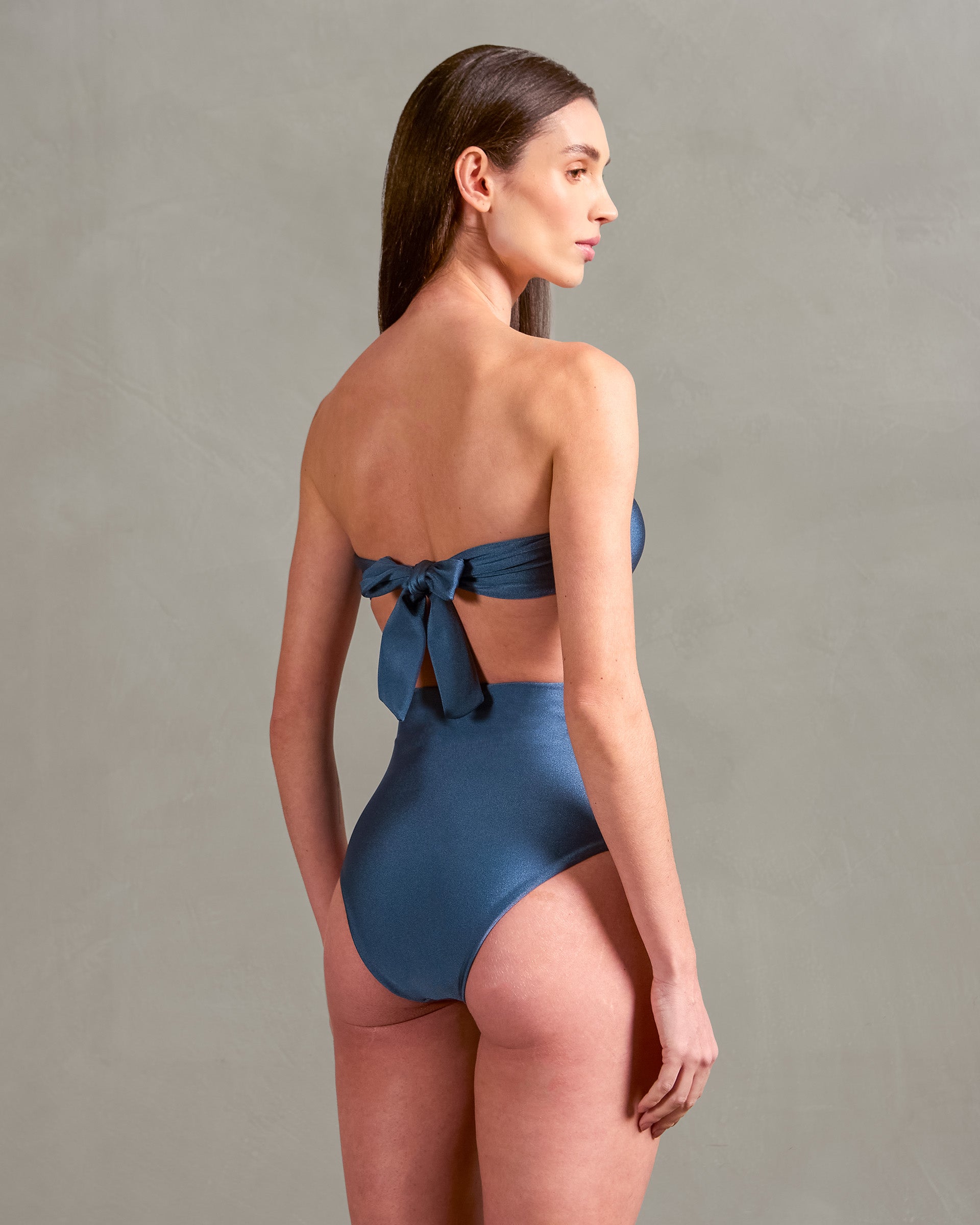 Model wearing the Vintage Lily Solid Appliqué High-Leg Bikini showcasing the back of it's authentic model, with antique blue and off white print, on a stretchy fabric.