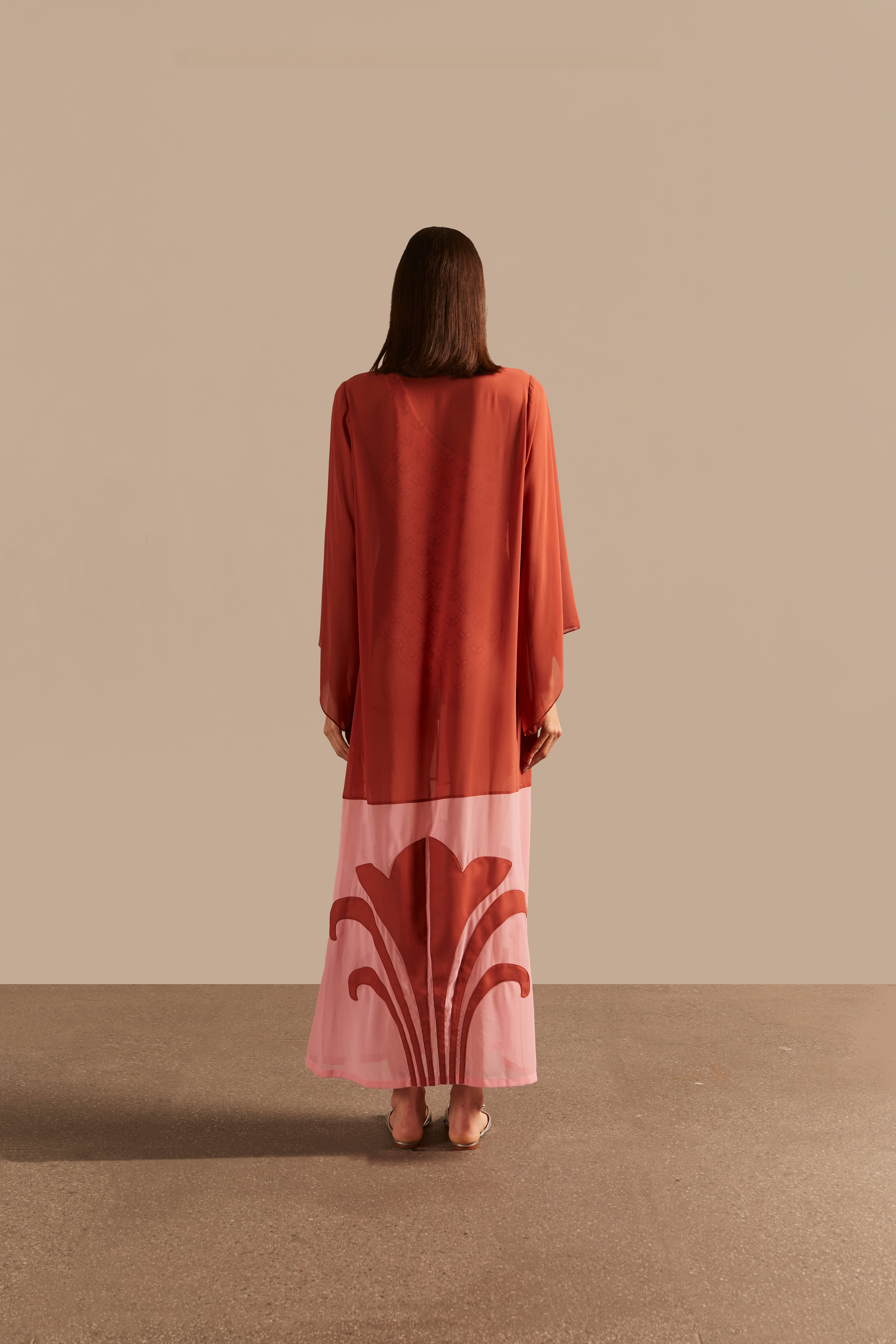 Model wearing the Vintage Lily Solid Appliqué Long Robe showcasing the back of it's vintage inspired dark red and pink print, on a polyester fabric.