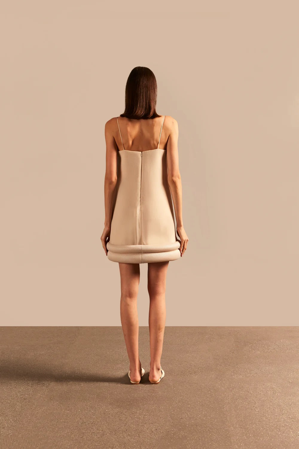 Model wearing the Vintage Lily Solid Beige Appliqué Short Dress showcasing the back of it's exquisite details, on a polyester fabric.