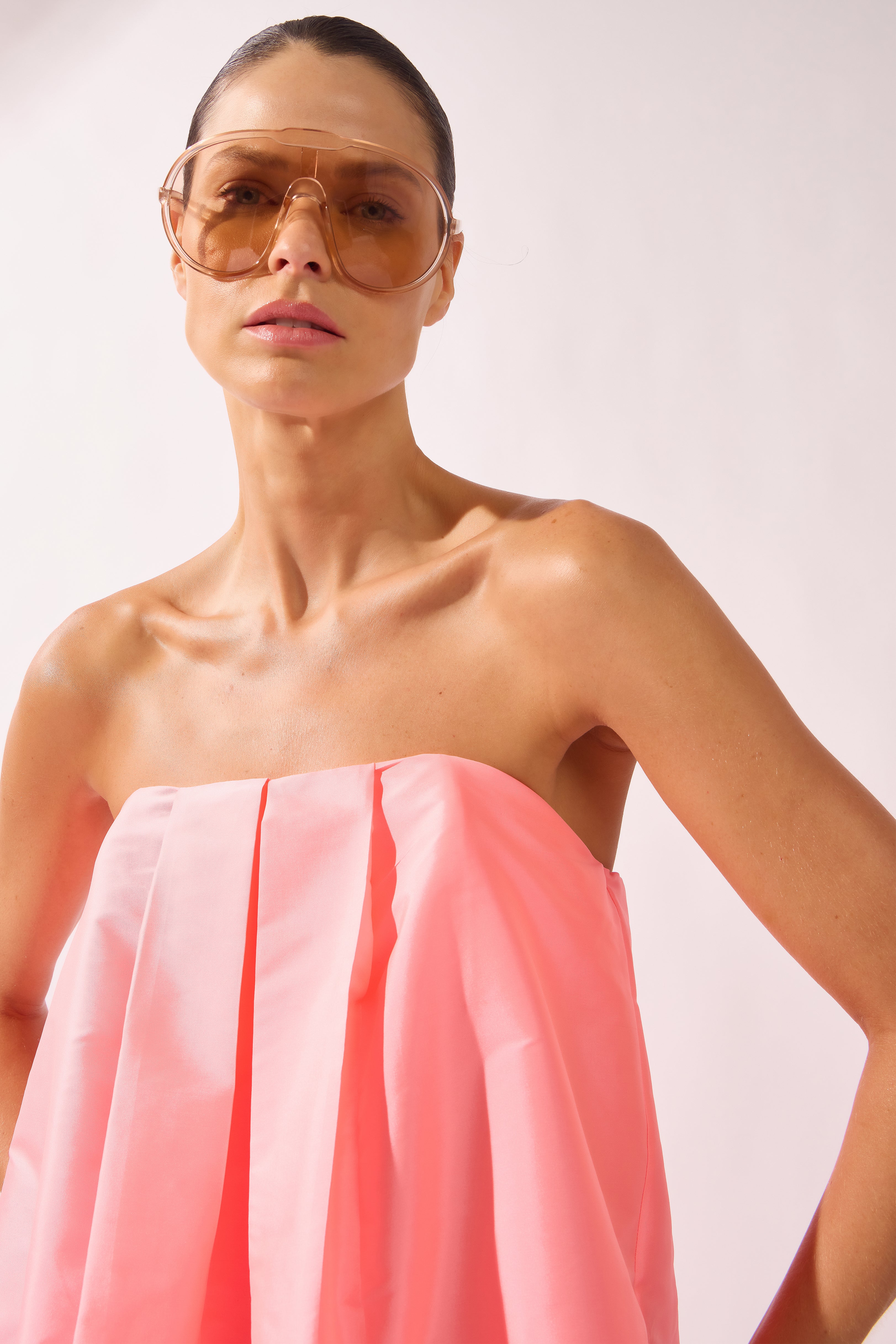 Model wearing the Voluminous Maxi Dress detail color flourescent pink made with 100% polyetser, styled for an evening look