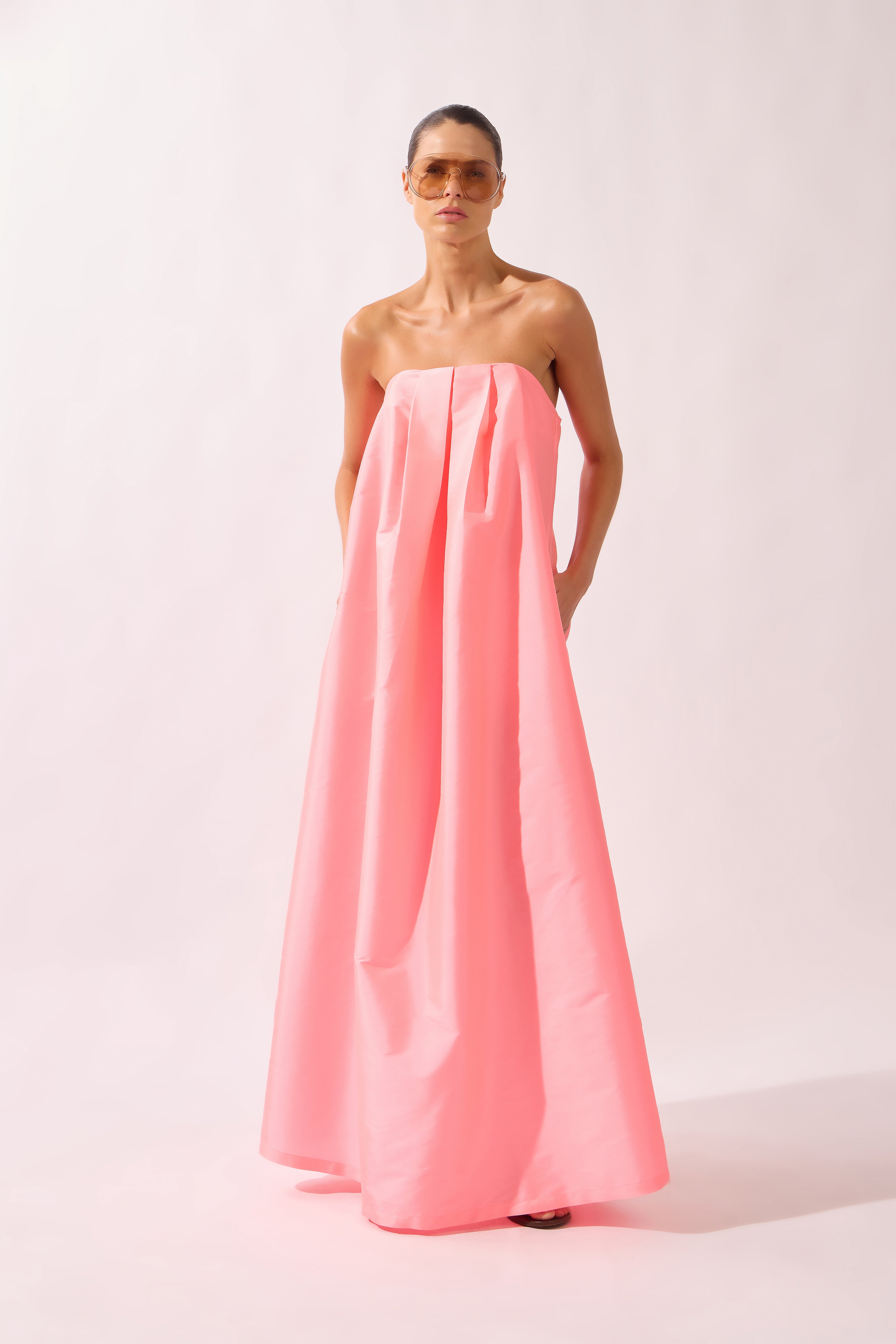 Model wearing the Voluminous Maxi Dress look color flourescent pink made with 100% polyetser, styled for an evening look
