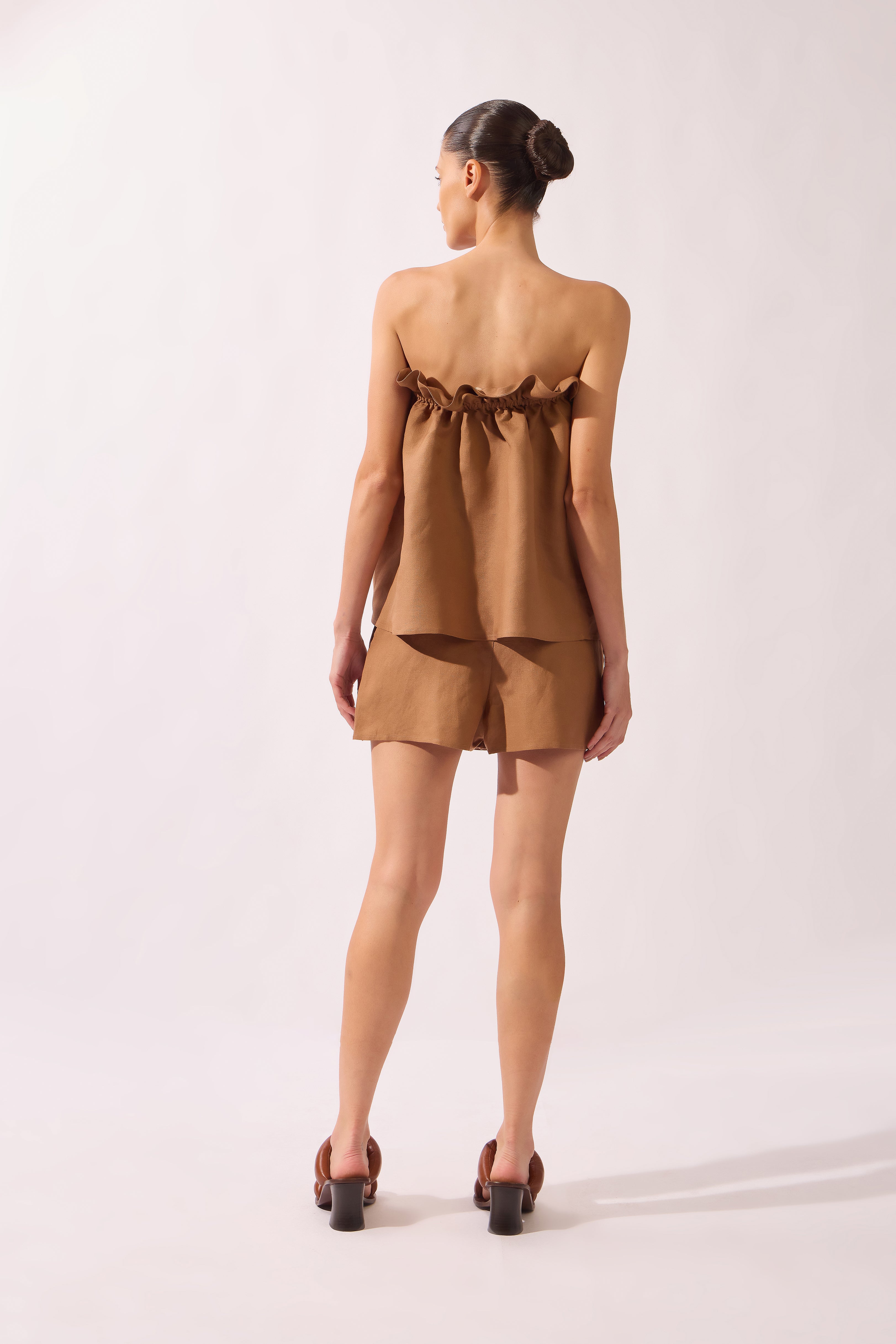 Model wearing the Belted Skort front  back color brown, made from 55% linen 45% viscose, styled for a resort look