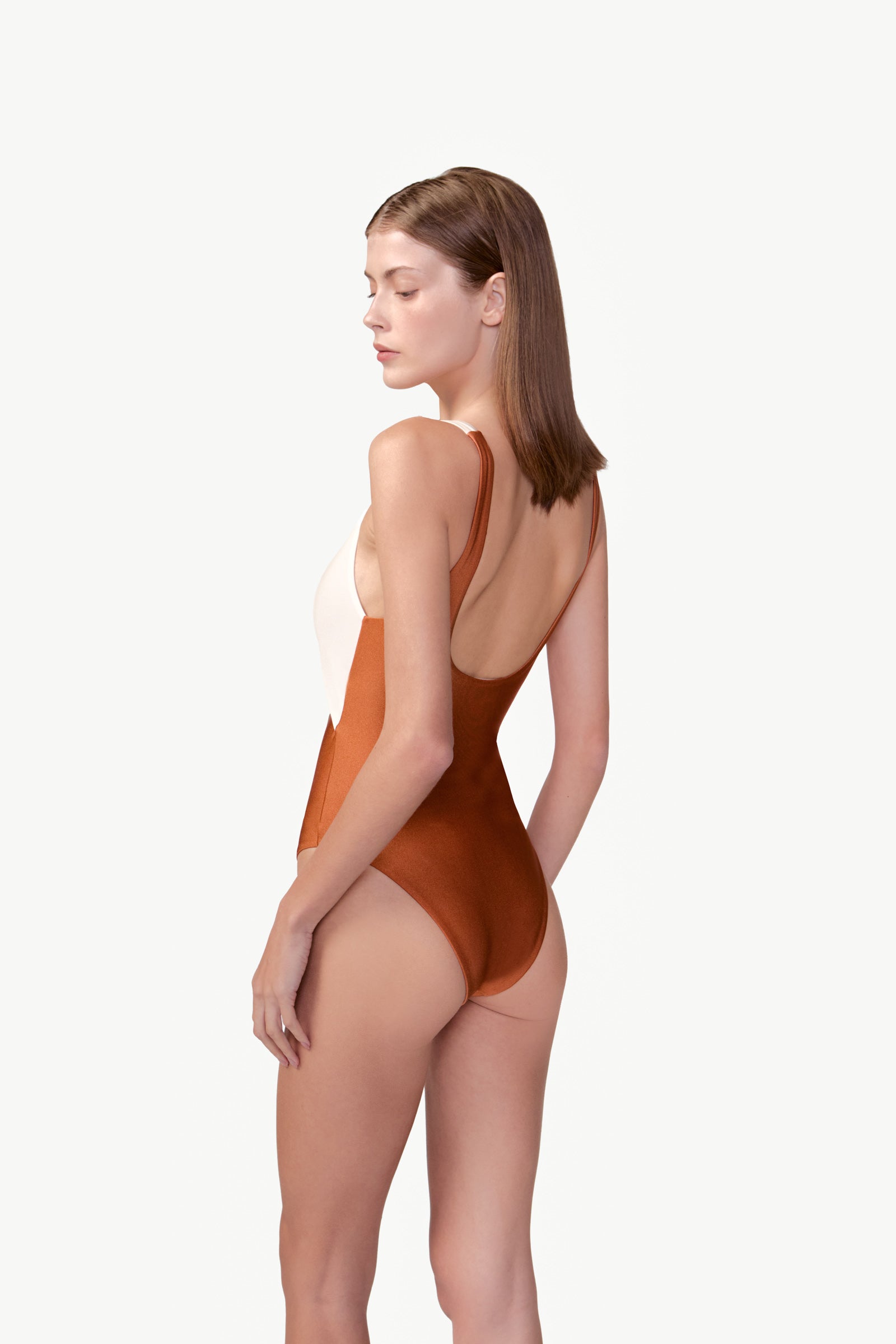 Model wearing the Bicolor Cut-Out Swimsuit back color cognac, made from 85% polyamide 15% elastane, styled for a beachwear look
