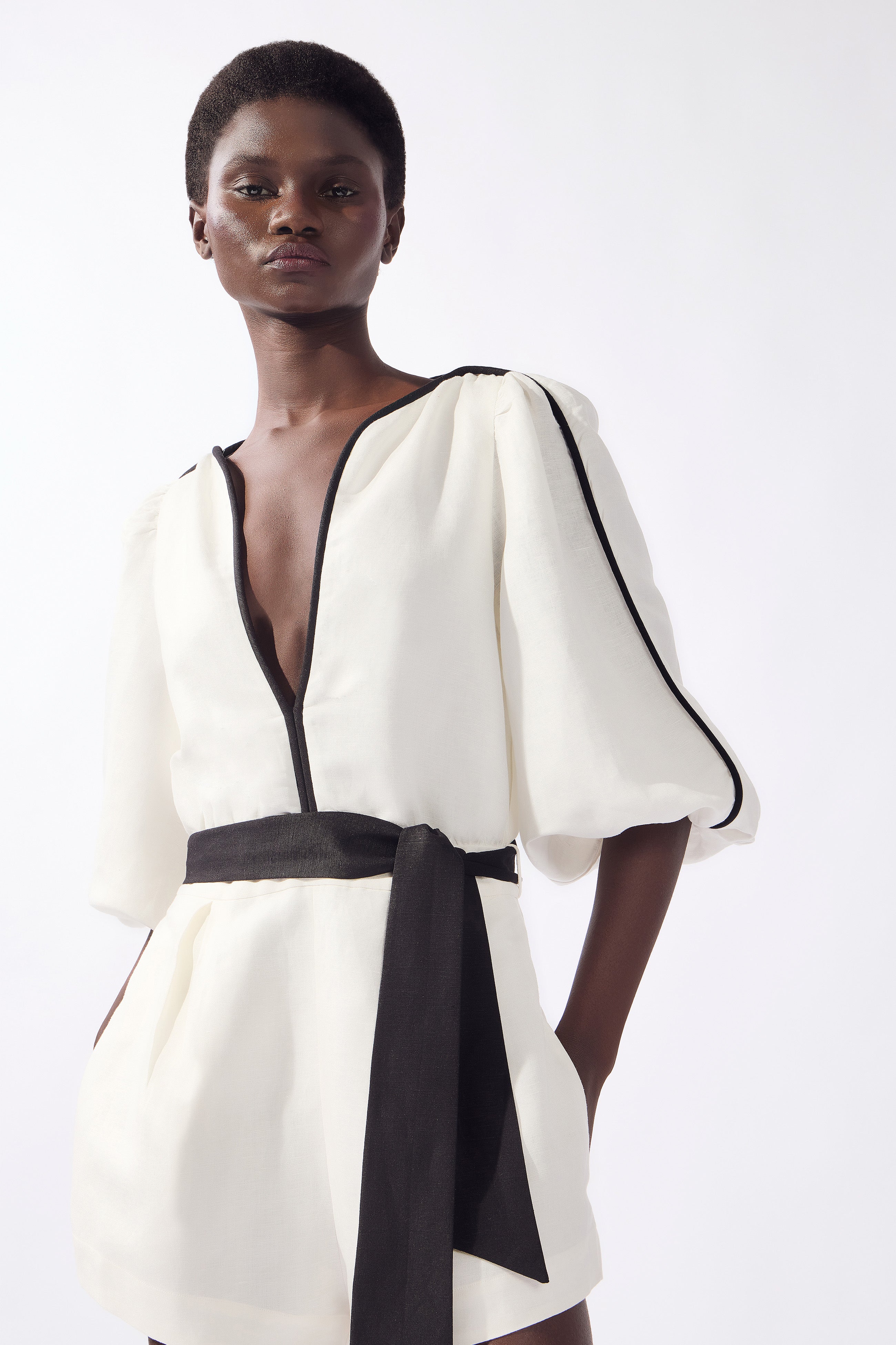 Model wearing the Bicolor Playsuit color off white, made from 55% linen 45% viscose, styled for a dinner look