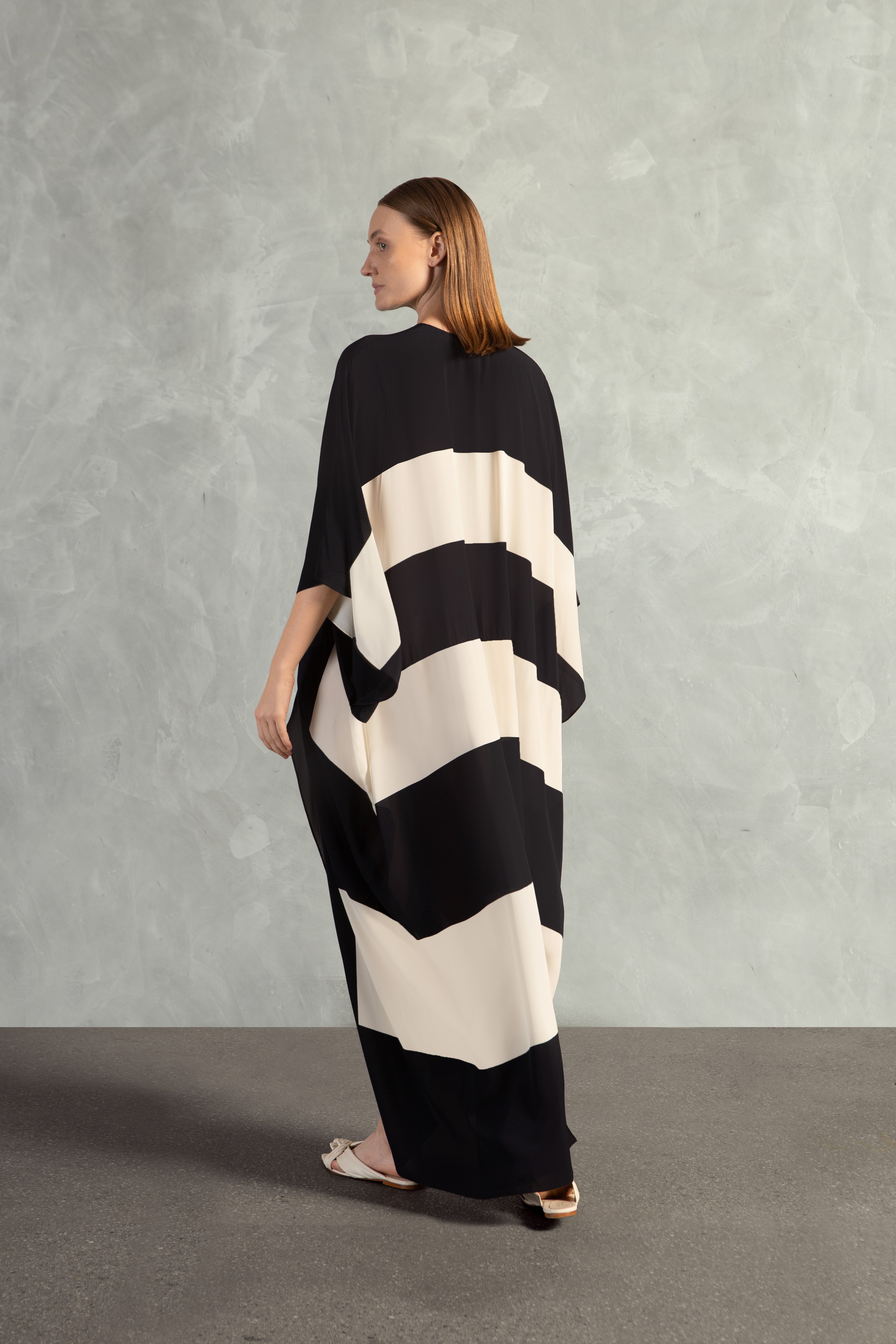 Model wearing the Bold Stripes Long Kaftan Back showcasing its Black print on 100% Viscose fabric, styled for an post-beach look.