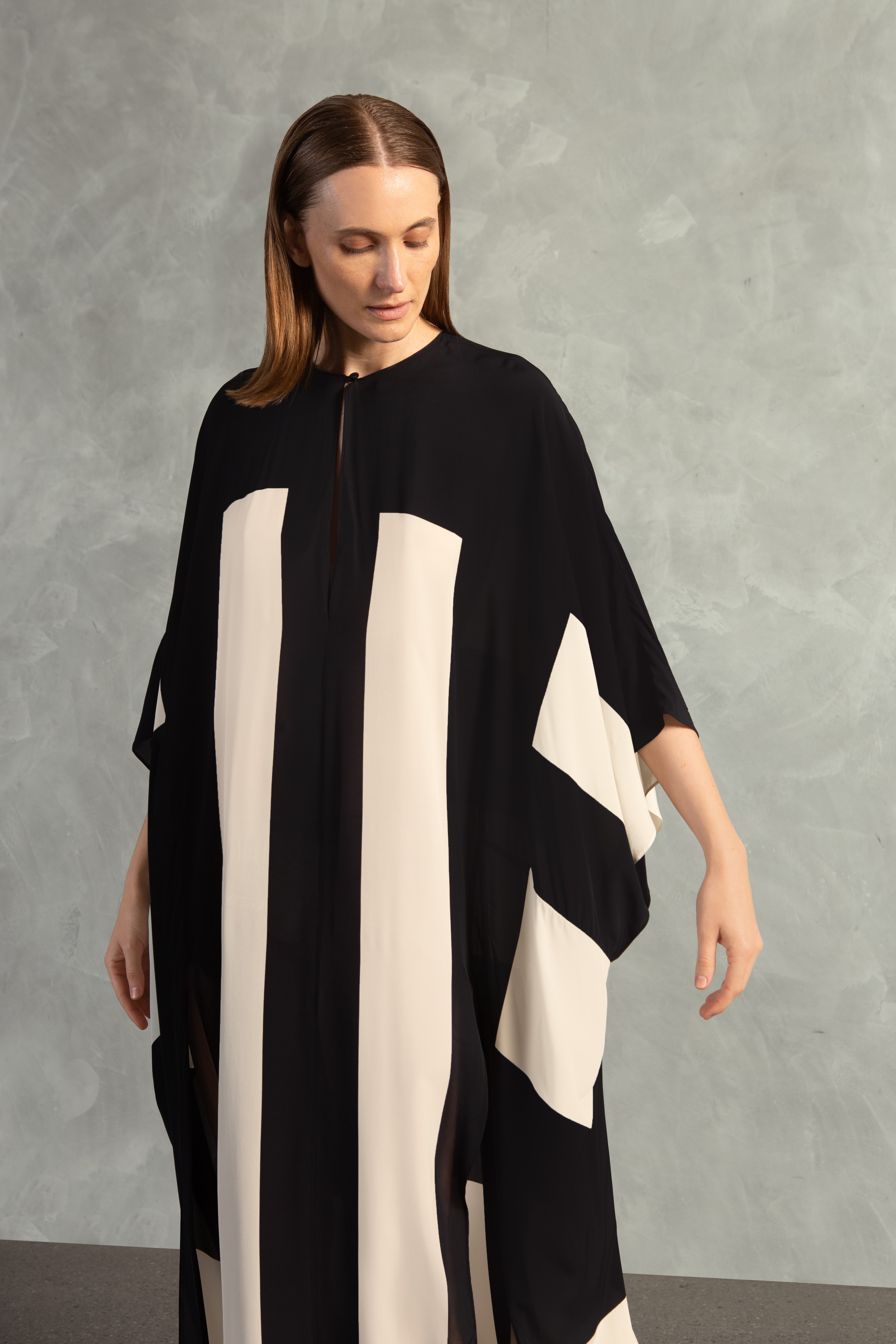 Model wearing the Bold Stripes Long Kaftan Detail showcasing its Black print on 100% Viscose fabric, styled for an post-beach look.