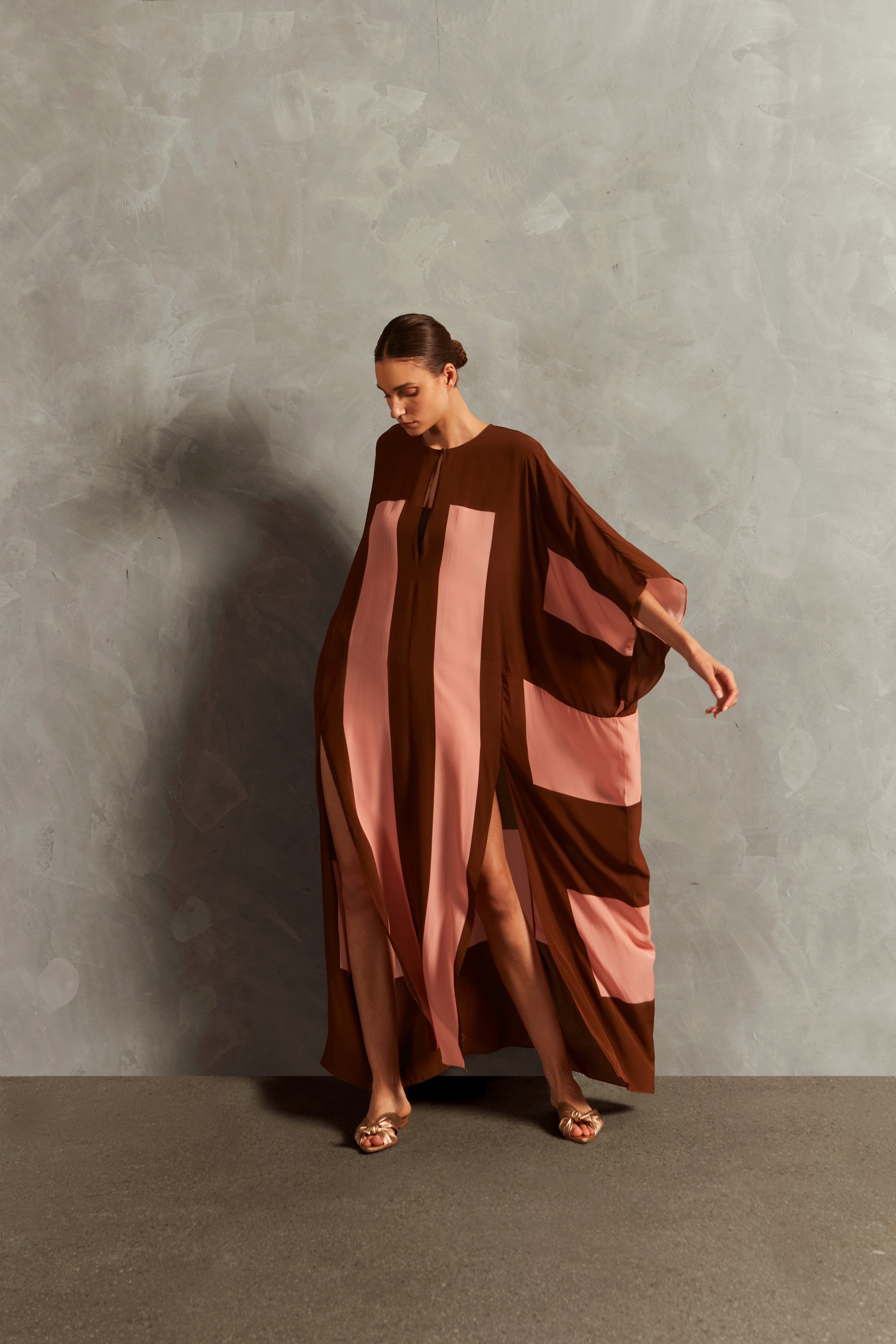 Model wearing the Bold Stripes Long Kaftan Front showcasing its Brown and Pink print on 100% Viscose fabric, styled for an post-beach look.