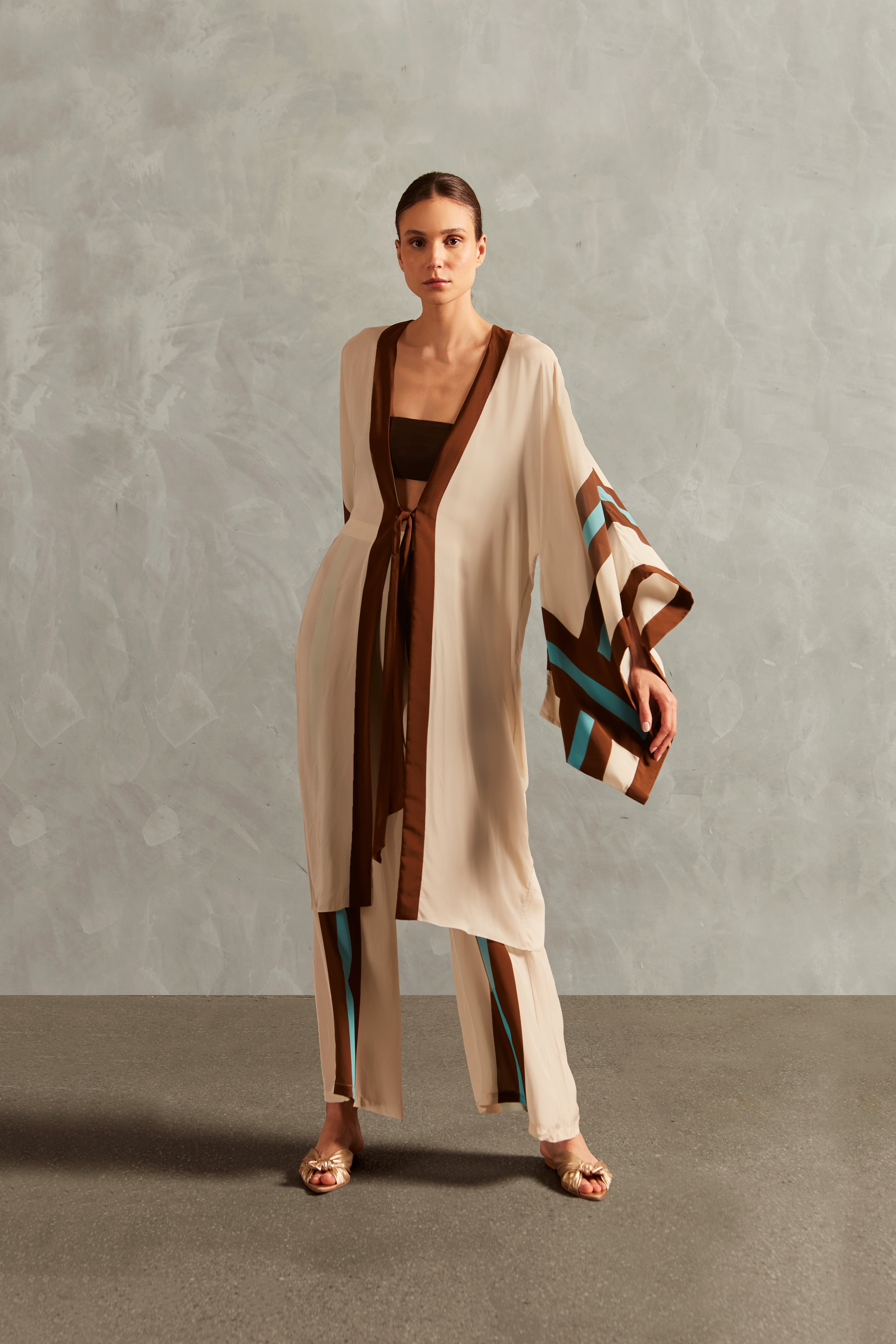 Model wearing the Bold Stripes Maxi Short Robe Front showcasing its Off White, Brown, Turquoise and Blue print on 100% Viscose fabric, styled for an afternoon look.