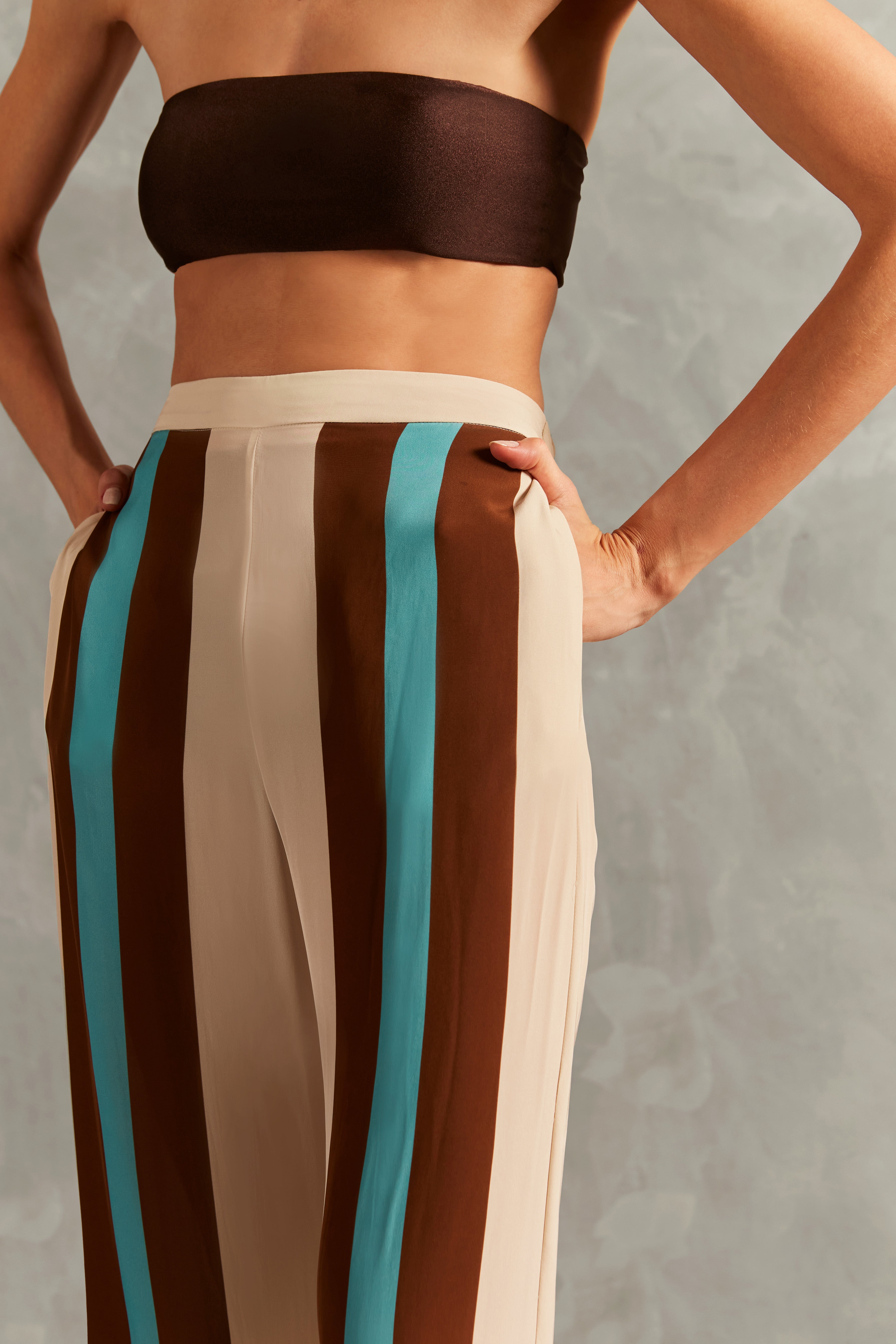 Model wearing the Bold Stripes Wide-Leg Pants Detail  showcasing its Off White/Brown/Turquoise Blue print on 100% Viscose fabric, styled for an afternoon look.