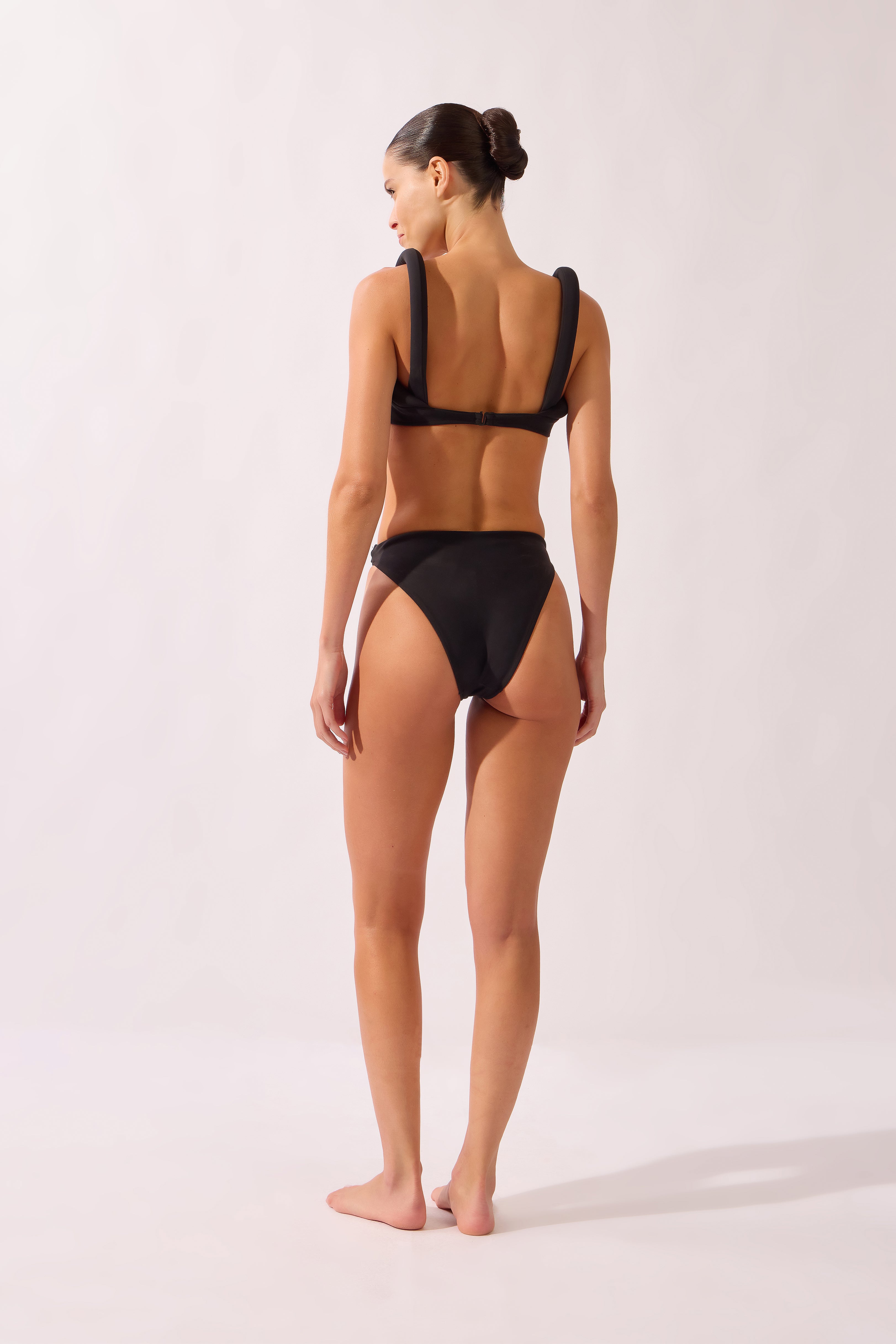 Model wearing the Bold Noir High-Leg Bikini back color black, made from 76.3% polyamide 23.7% elastane, styled for a beachwear look