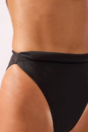 Model wearing the Bold Noir High-Leg Bikini detail bottom color black, made from 76.3% polyamide 23.7% elastane, styled for a beachwear look