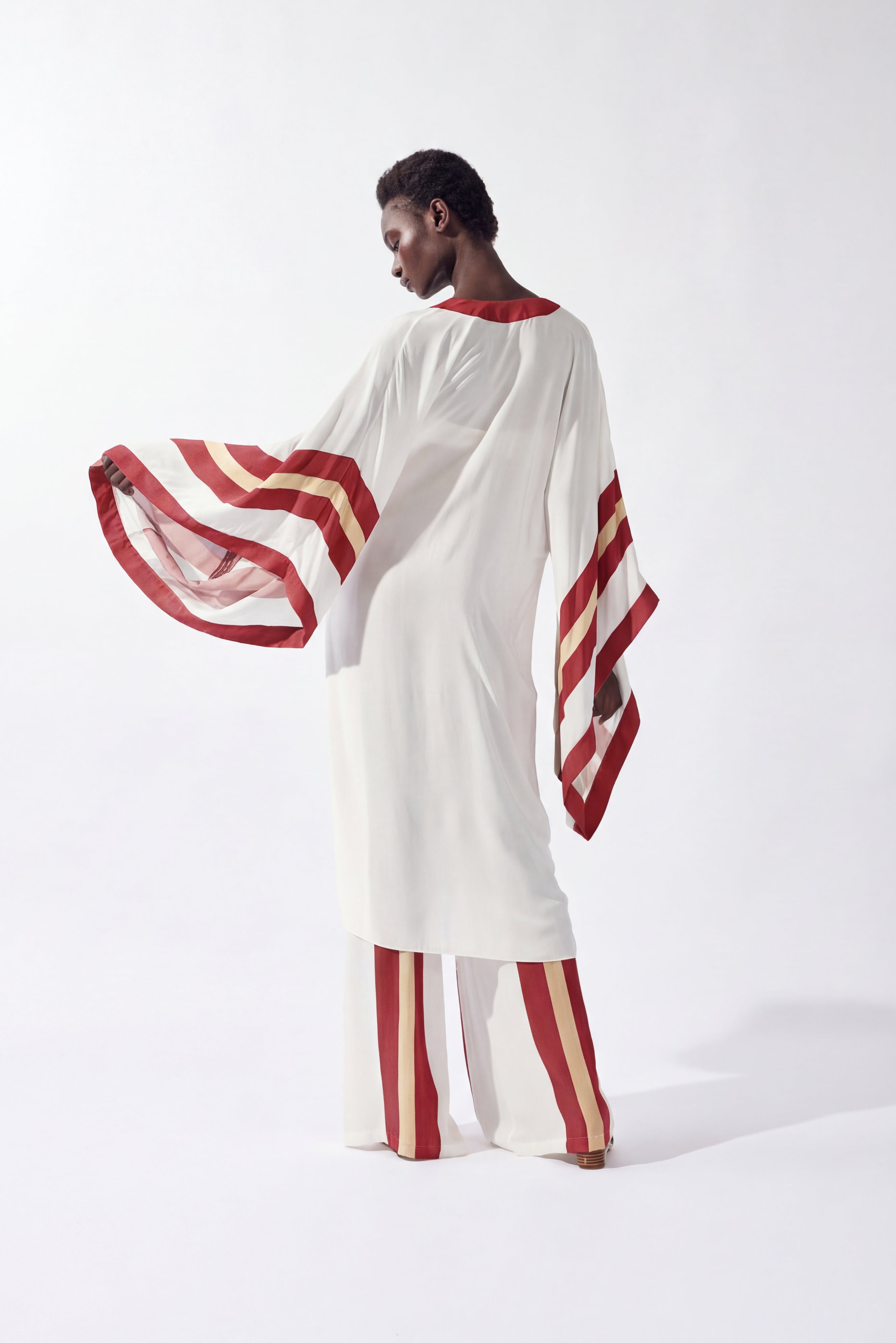 Model wearing the Bold Stripes Robe back, color off white, burgundy, beige, made from 100% viscose, styled for a resort look