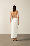 Model wearing the Coquille De Mer Long Skirt back, color off white with 76.3% polyamide 23.7% elastane, styled for a drink at sundown.