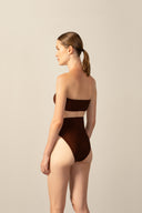 Model wearing the Corduroy High-Leg Bandeau Bikini cacau color back from the HS25 with 85% Polyamide 15% Elastane styled for a beach look.   