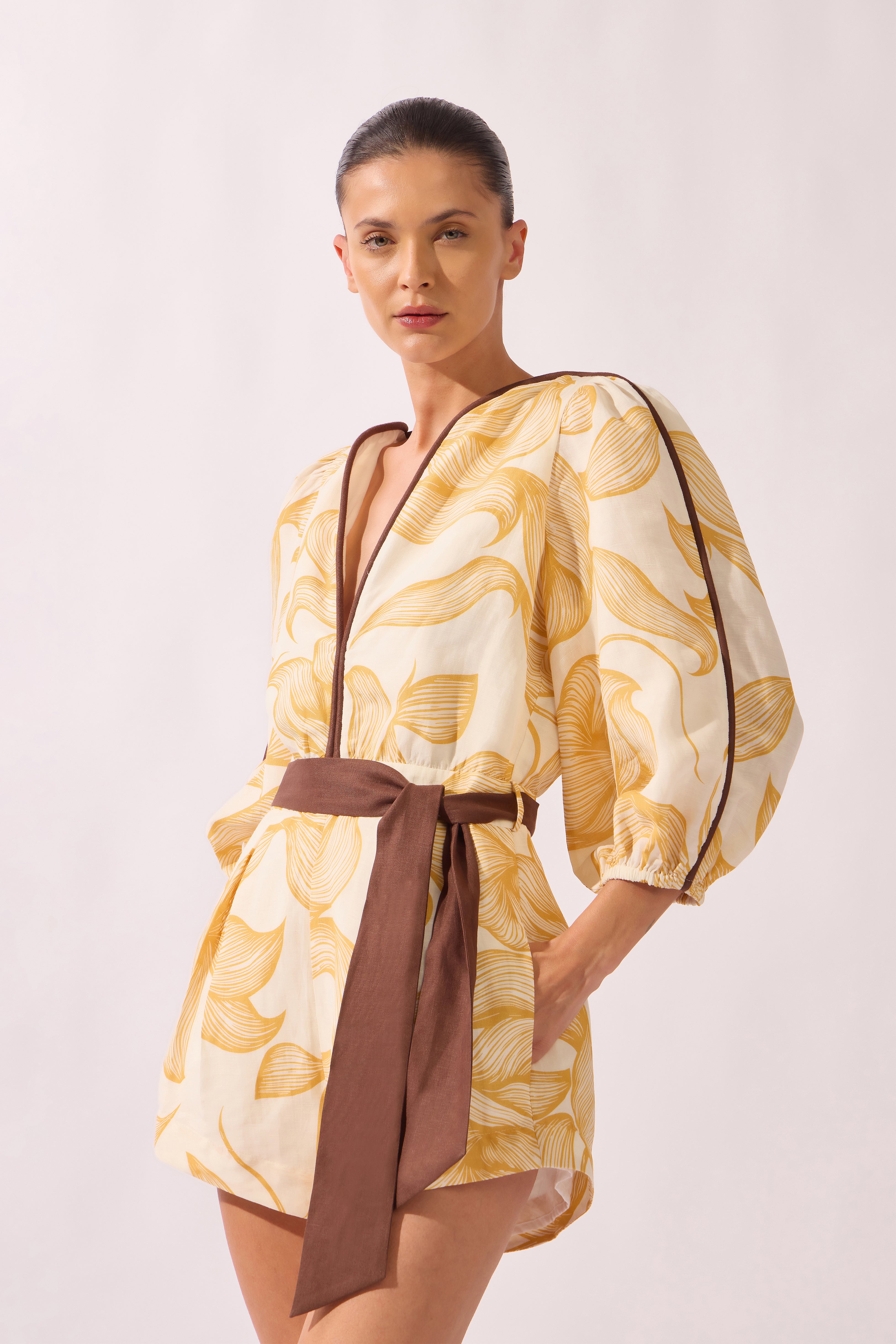 Model wearing the Foliage Romper look color cashew yellow, made from 55% linen 45% viscose, styled for a resort look