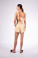 Model wearing the Foliage Shorts back color cashew yellow, made from 55% linen 45% viscose, styled for a resort look