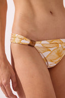 Model wearing the Foliage Triangle Bikini detail bottom color cashew yellow, made from 85% polyamide 15% elastane, styled for a beachwear look