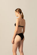 Model wearing the Geometric Bandeau Bikini black back from the HS25 with 85% Polyamide 15% Elastane styled for a beach look.   