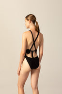 Model wearing the Geometric Cross-Back Swimsuit black back from the HS25 with 85% Polyamide 15% Elastane styled for a beach look.   